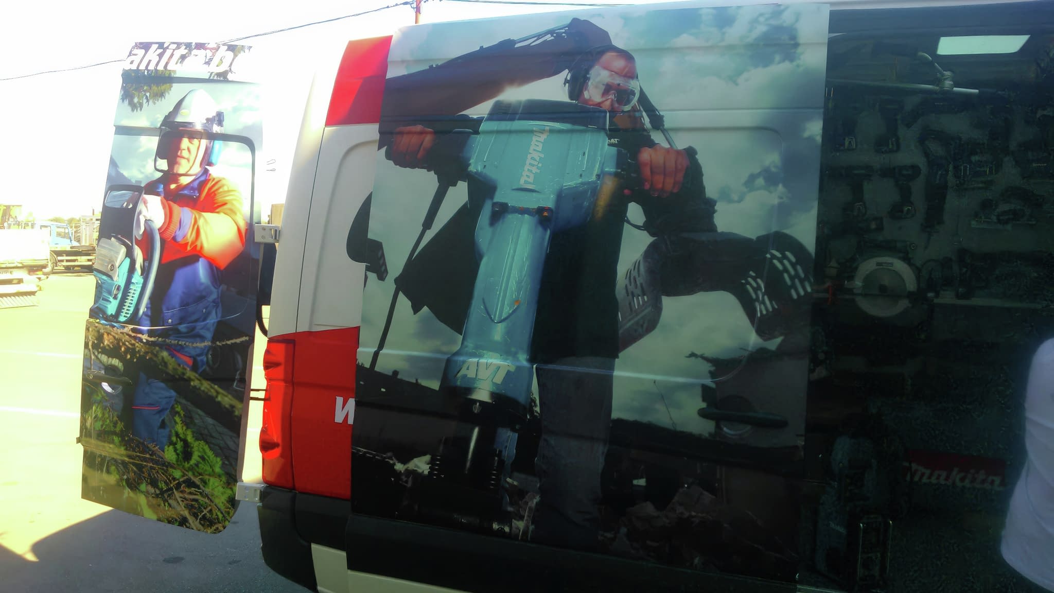 Брандиран бус с рекламно фолио на Makita, изобразяващ работници с професионални инструменти в действие.