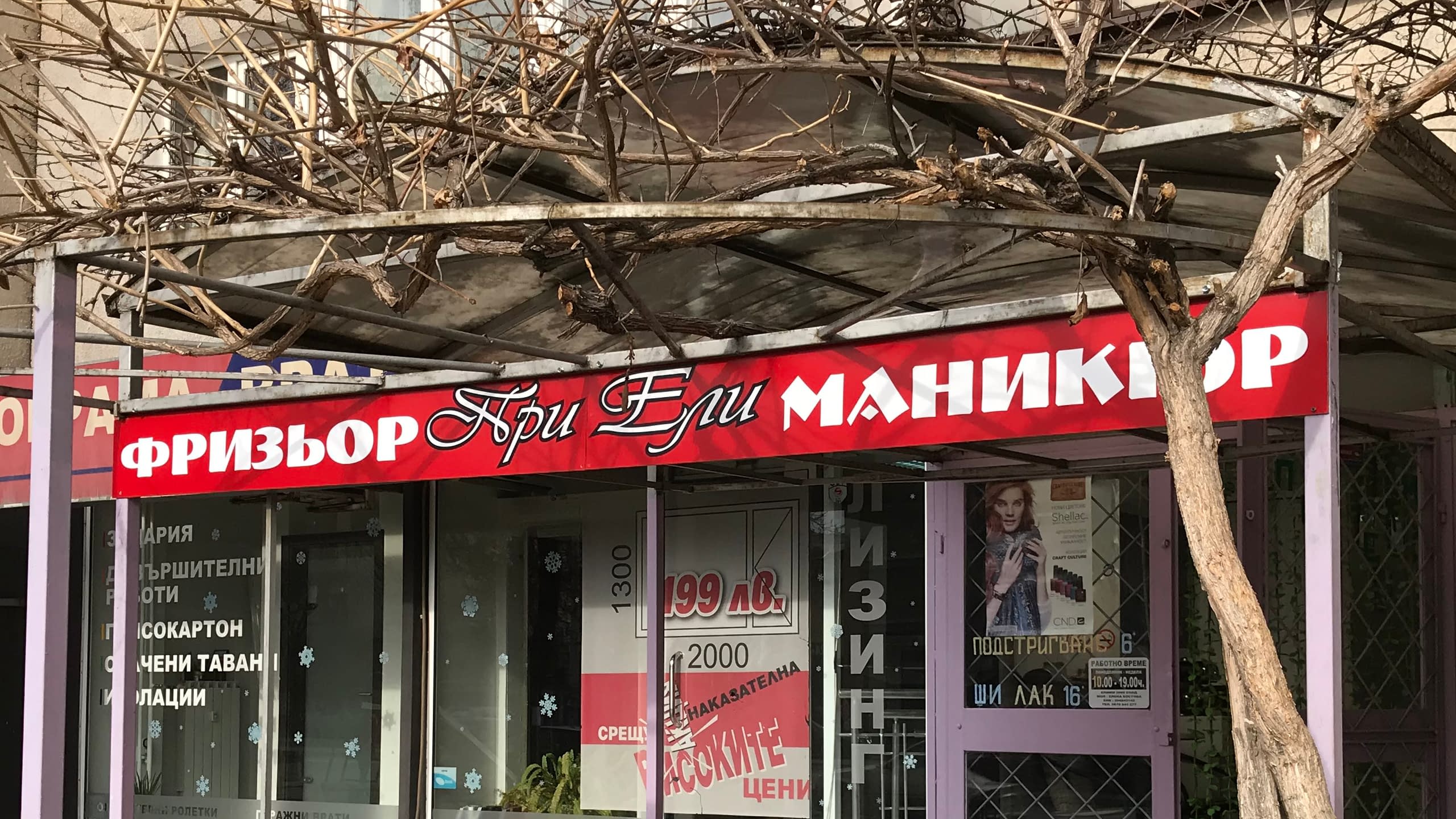 Фирмена табела тип фриз за салон "При Ели" с червен фон и бял надпис "ФРИЗЬОР МАНИКЮР", монтирана над витрина.