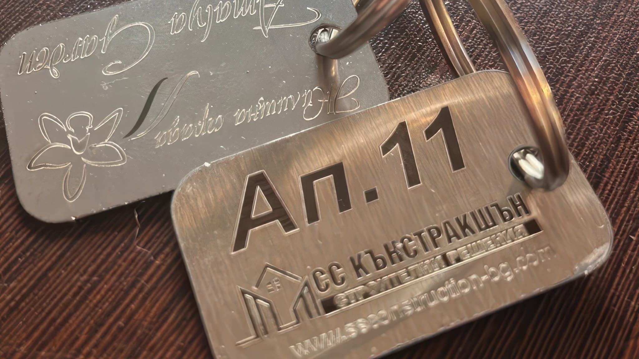 Метални ключодържатели с лазерно гравирани надписи и лого – апартамент 11 и фирмена информация.