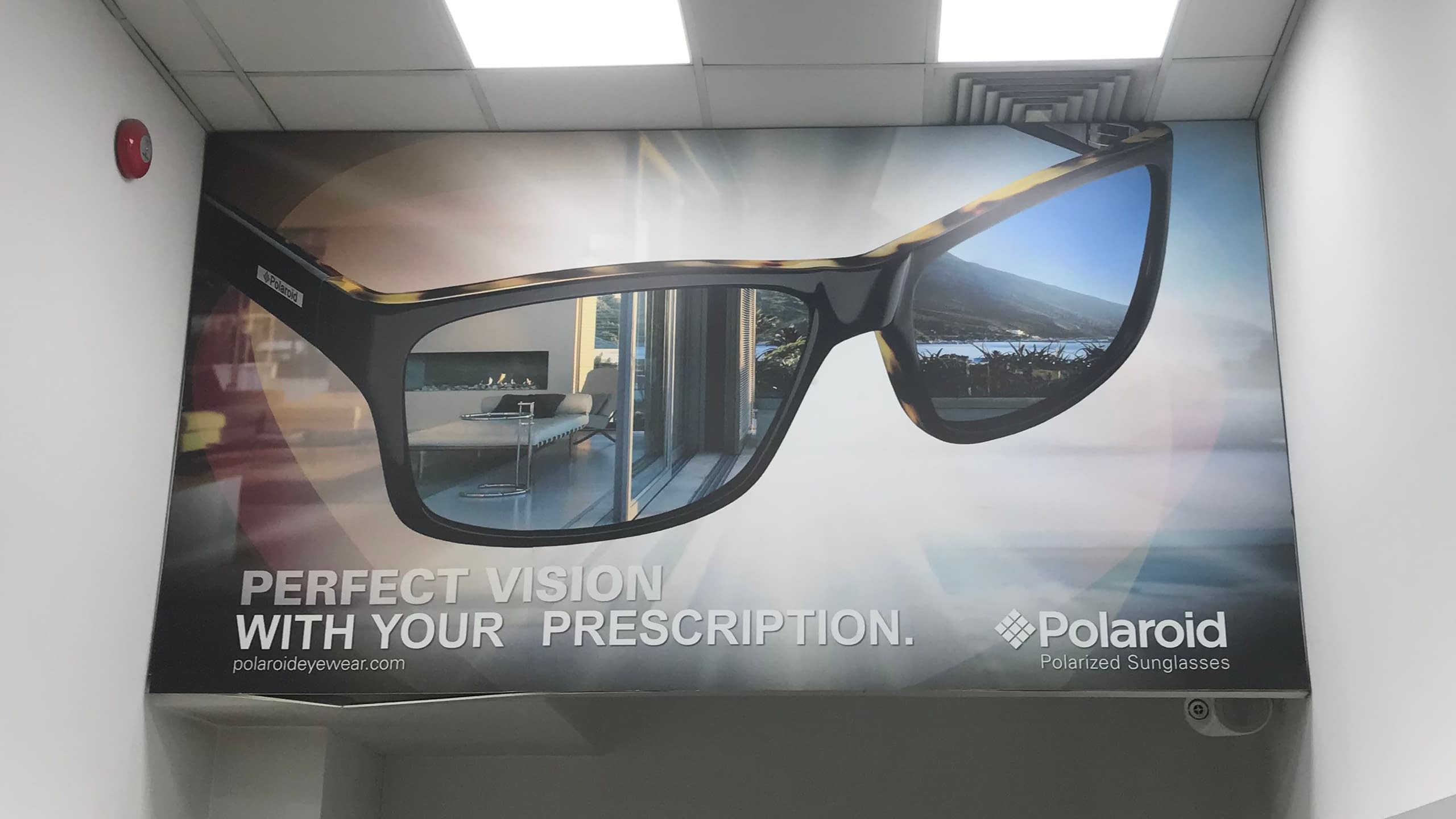 Рекламен фототапет по поръчка с брандинг на Polaroid, монтиран на стена в търговски обект.