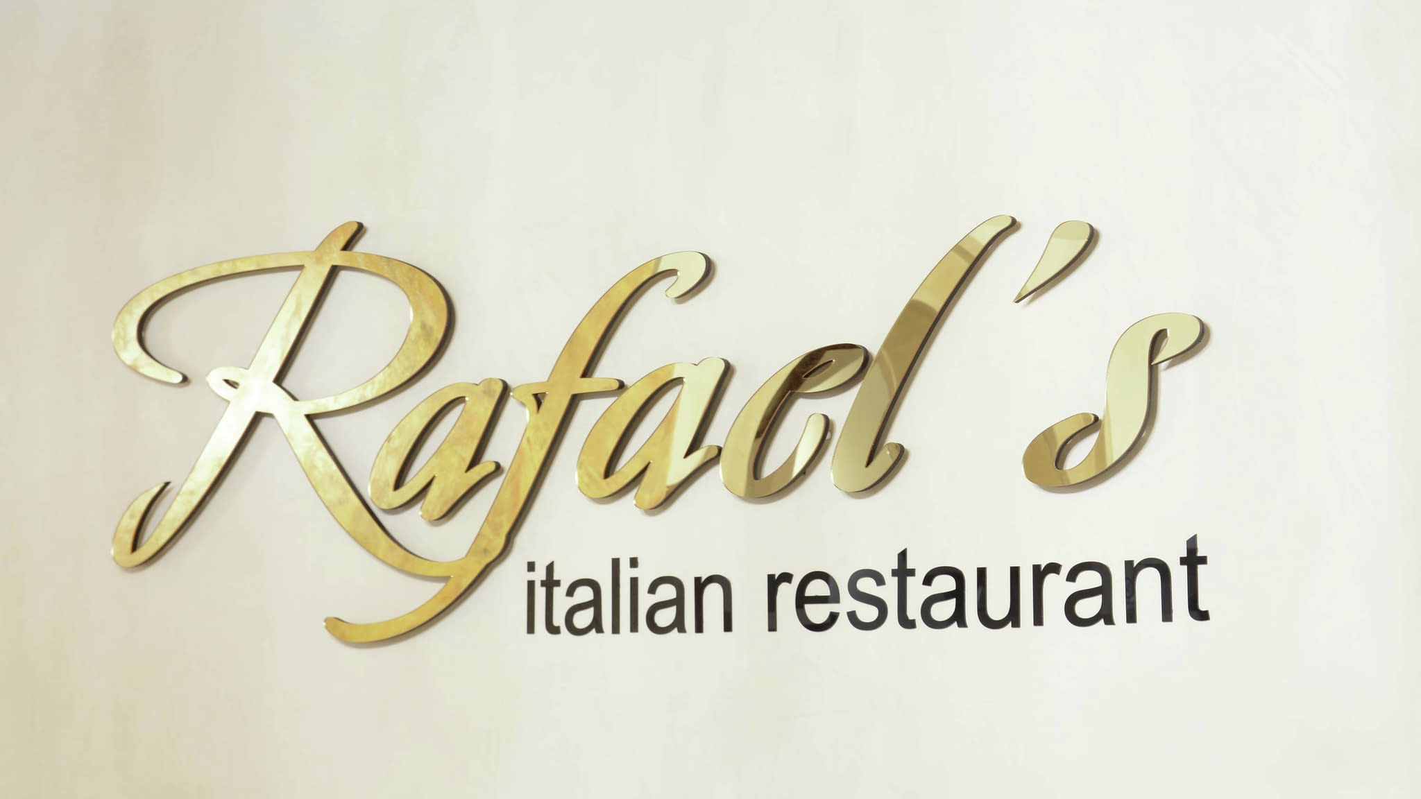 Обемни златни букви 'Rafael's Italian Restaurant' на стена – елегантна интериорна табела за италиански ресторант.
