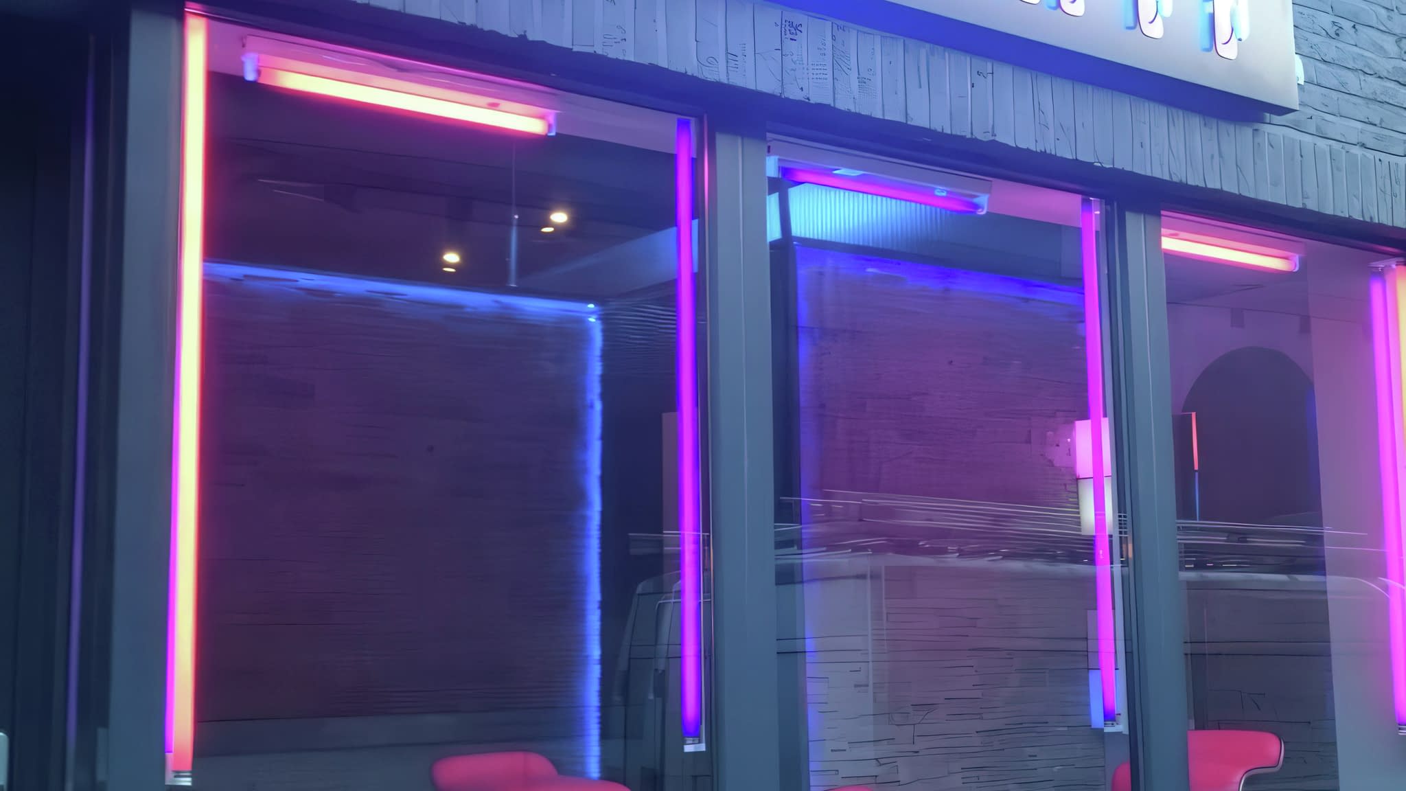 Модерна неонова реклама с лилави и сини светлинни елементи, монтирана на витрина на търговски обект.