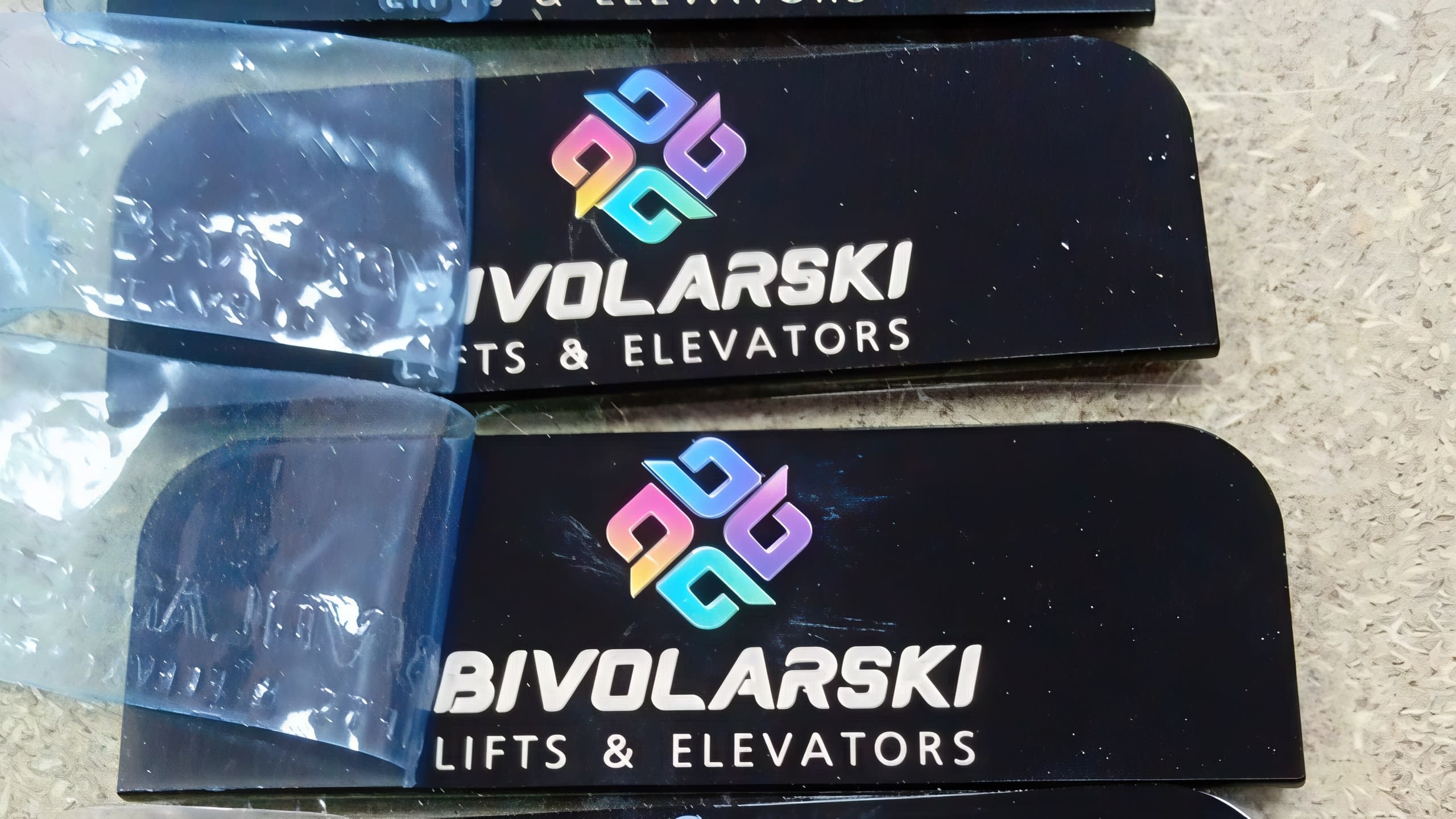 Малки брандирани офис табели в процес на изработка за фирма "BIVOLARSKI LIFTS & ELEVATORS" с цветно лого.