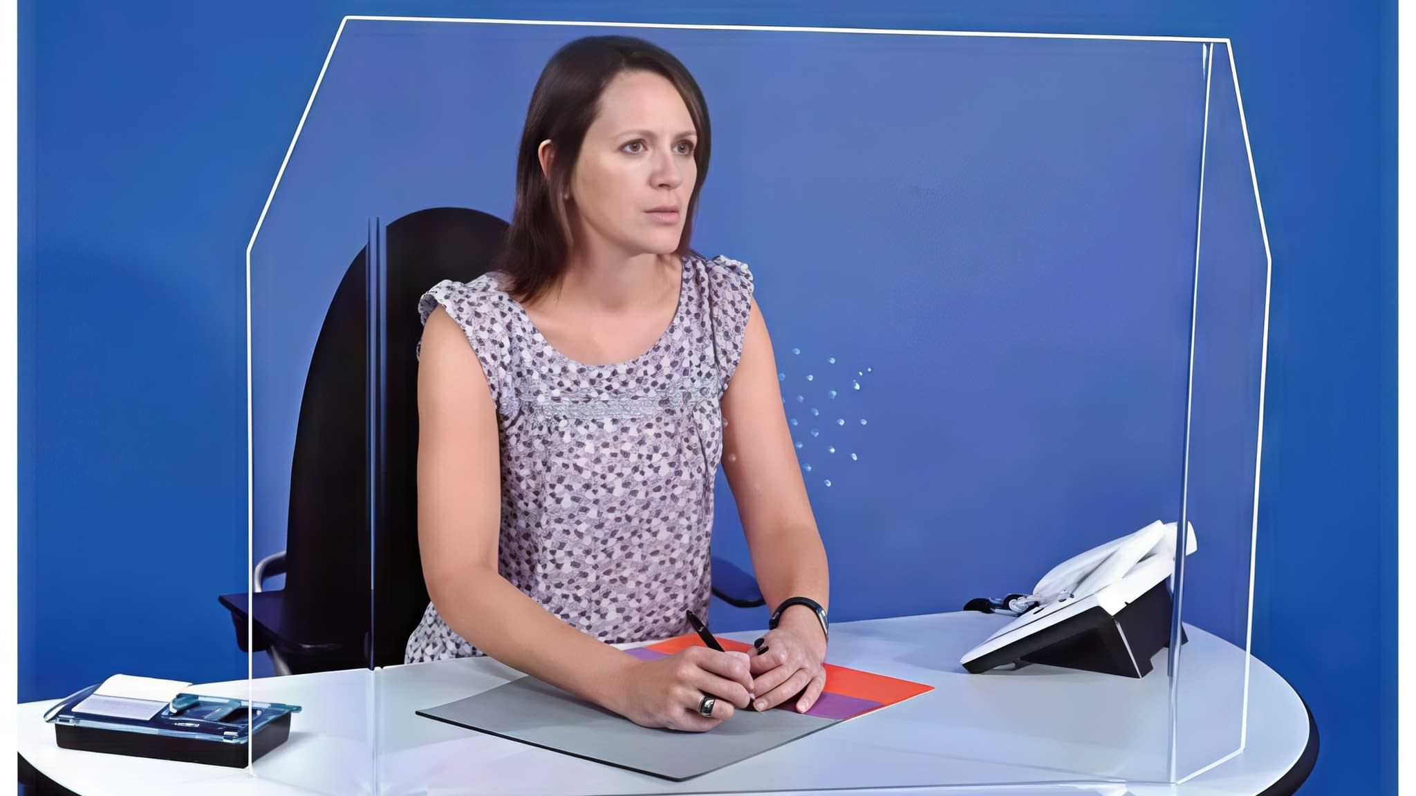 Служителка зад плексигласова защитна преграда на бюро – ефективна мярка за безопасност срещу разпространение на вируси в офиси и приемни.