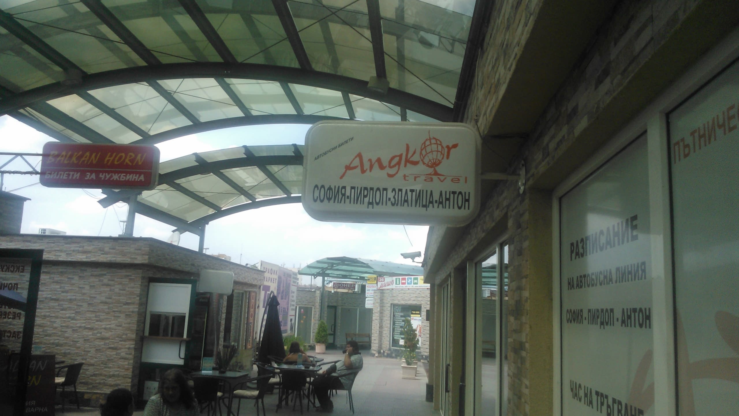 Двустранна правоъгълна табела за транспортна фирма, монтирана на стена на спирка или автогара.