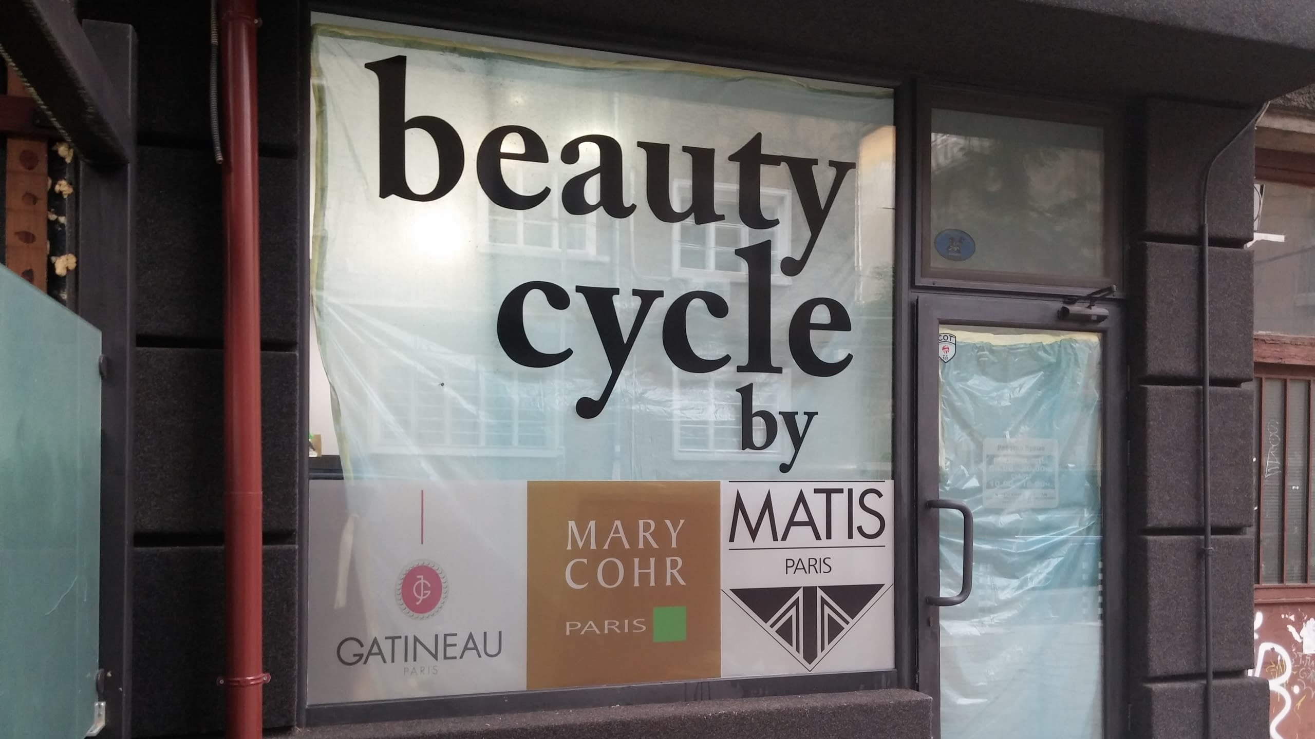 Външен изглед на витрина, облепена с фолио, и тъмната фасада на сградата.