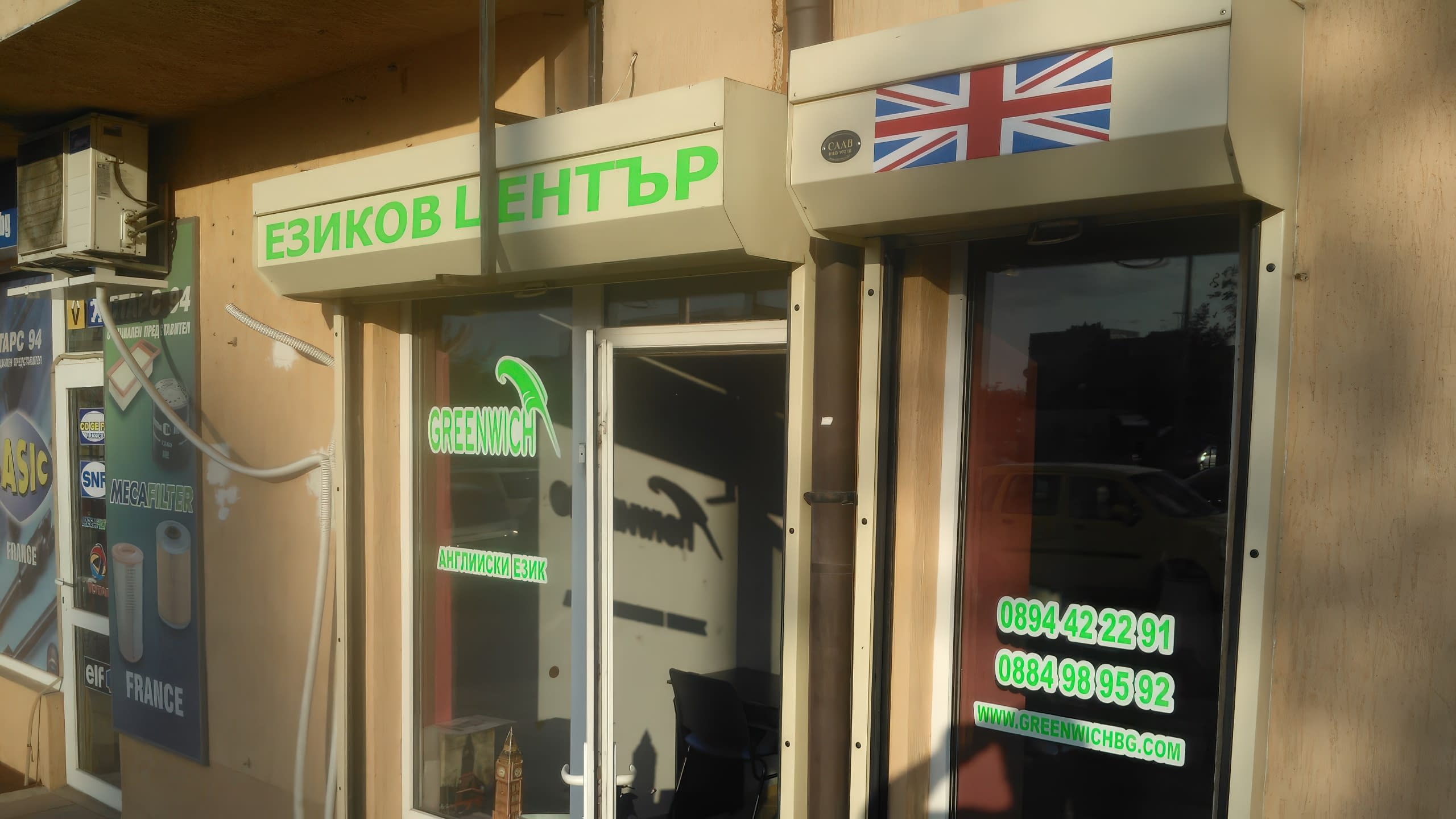 Витрина на учебен център със зелени надписи по стъклата, контакти и табели над тях.