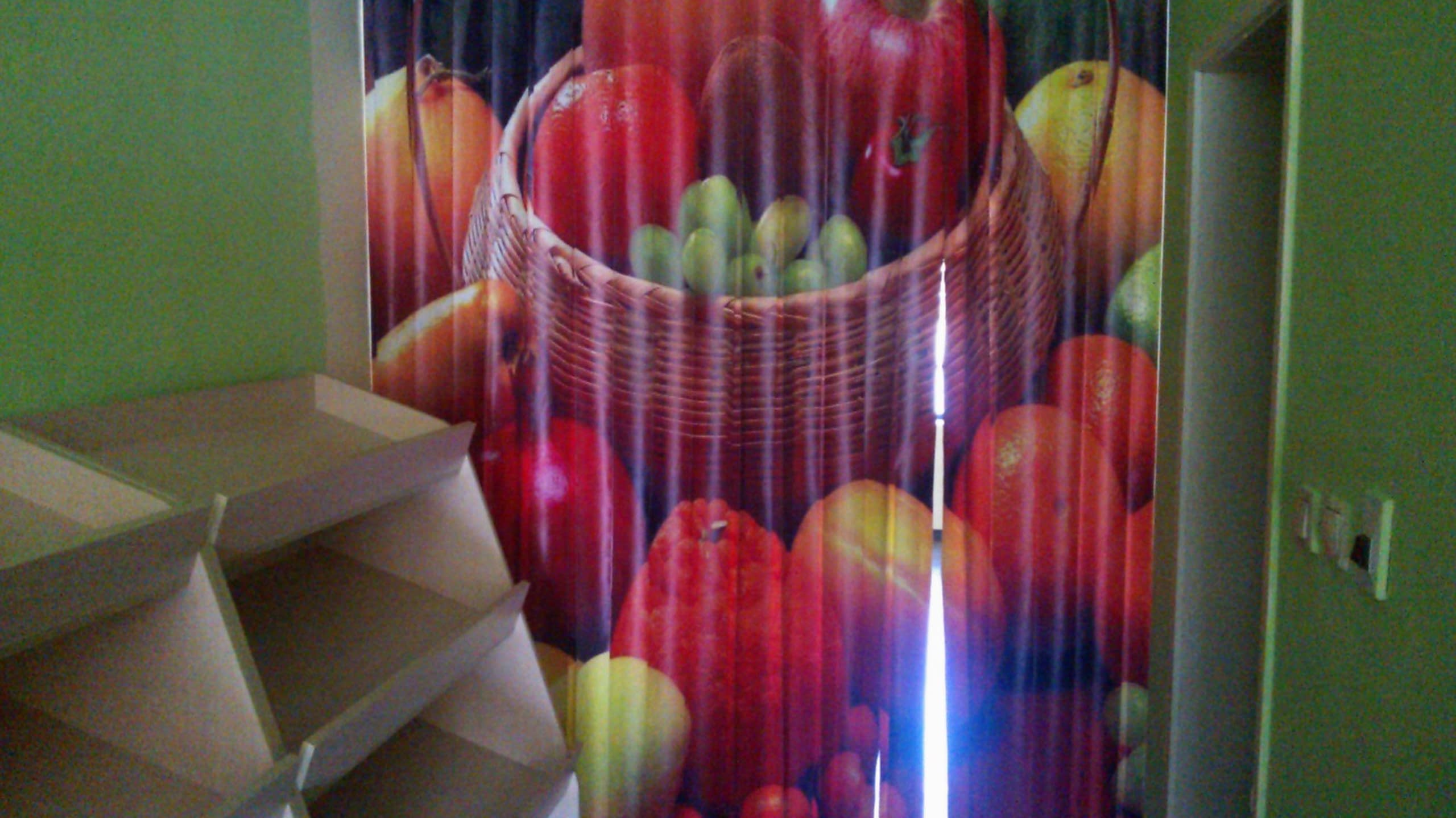 Интериорна стена в магазин, декорирана с голямо цветно изображение на кошница с плодове, отпечатано върху вертикални ленти.