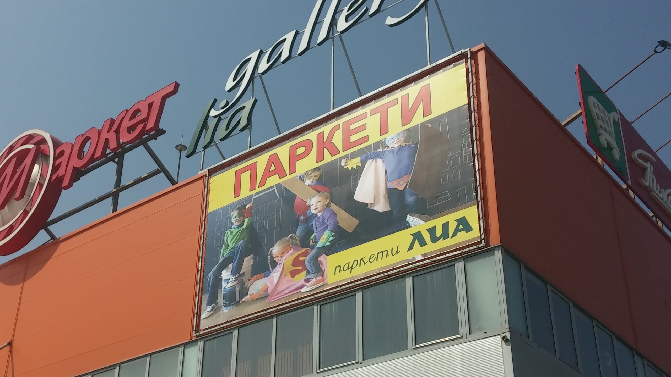 Близък план на рекламно пано за паркети, показващо деца, които си играят на пода.