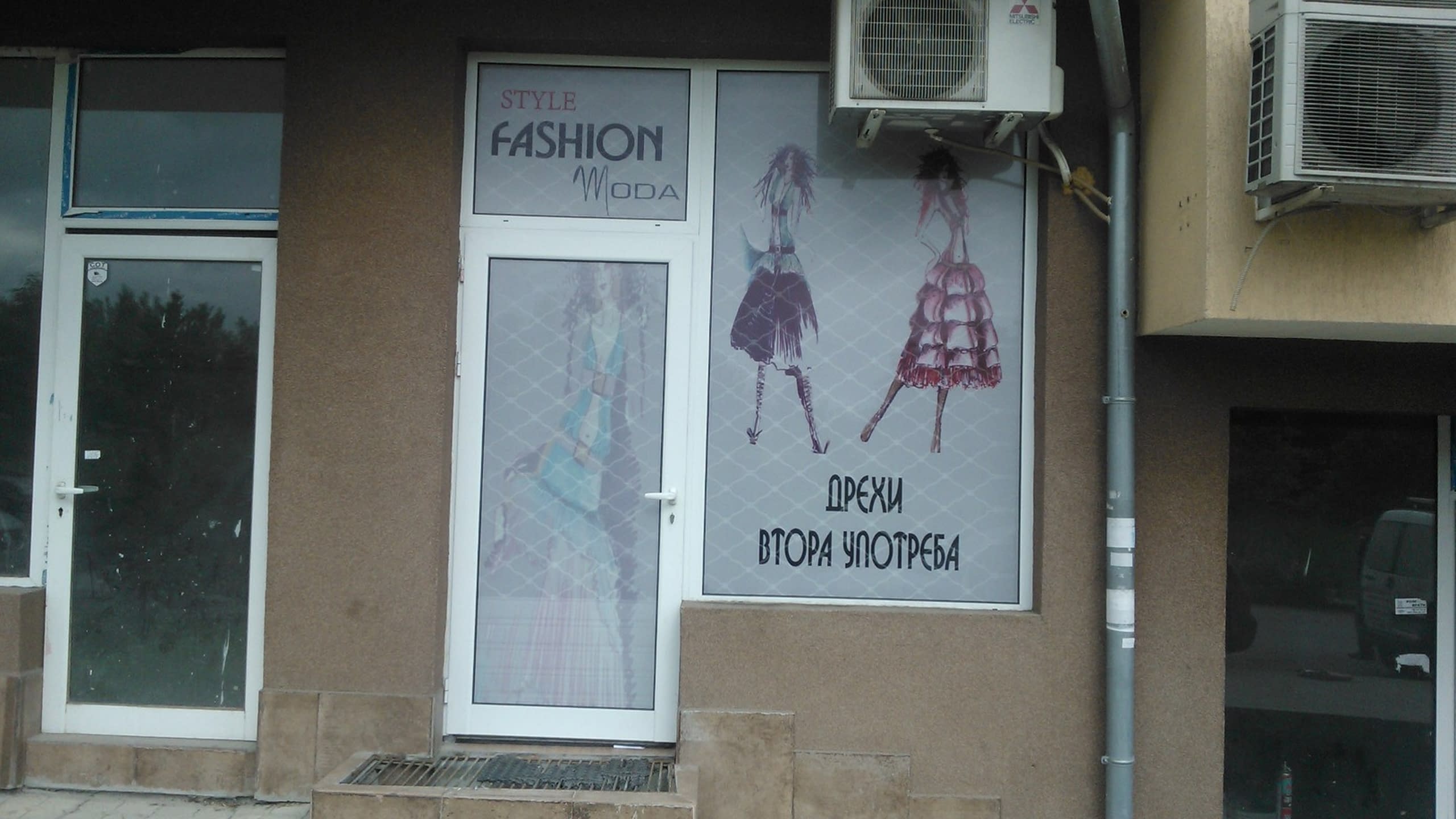 Витрина на магазин за дрехи, облепена с фолио с модни илюстрации и надпис "Дрехи втора употреба".