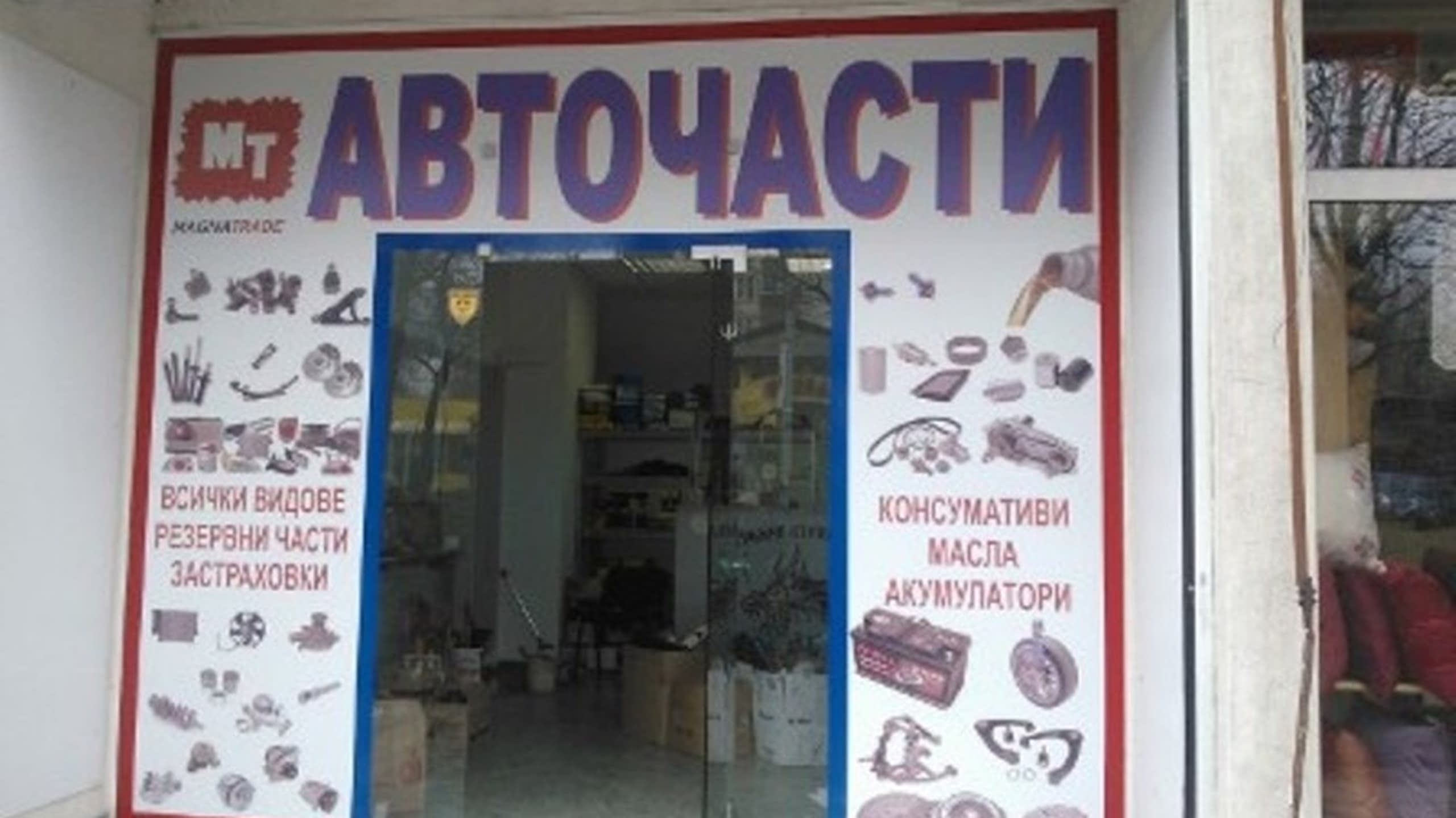 Вход на магазин за авточасти, облепен с фолио с надписи и илюстрации на различни резервни части.