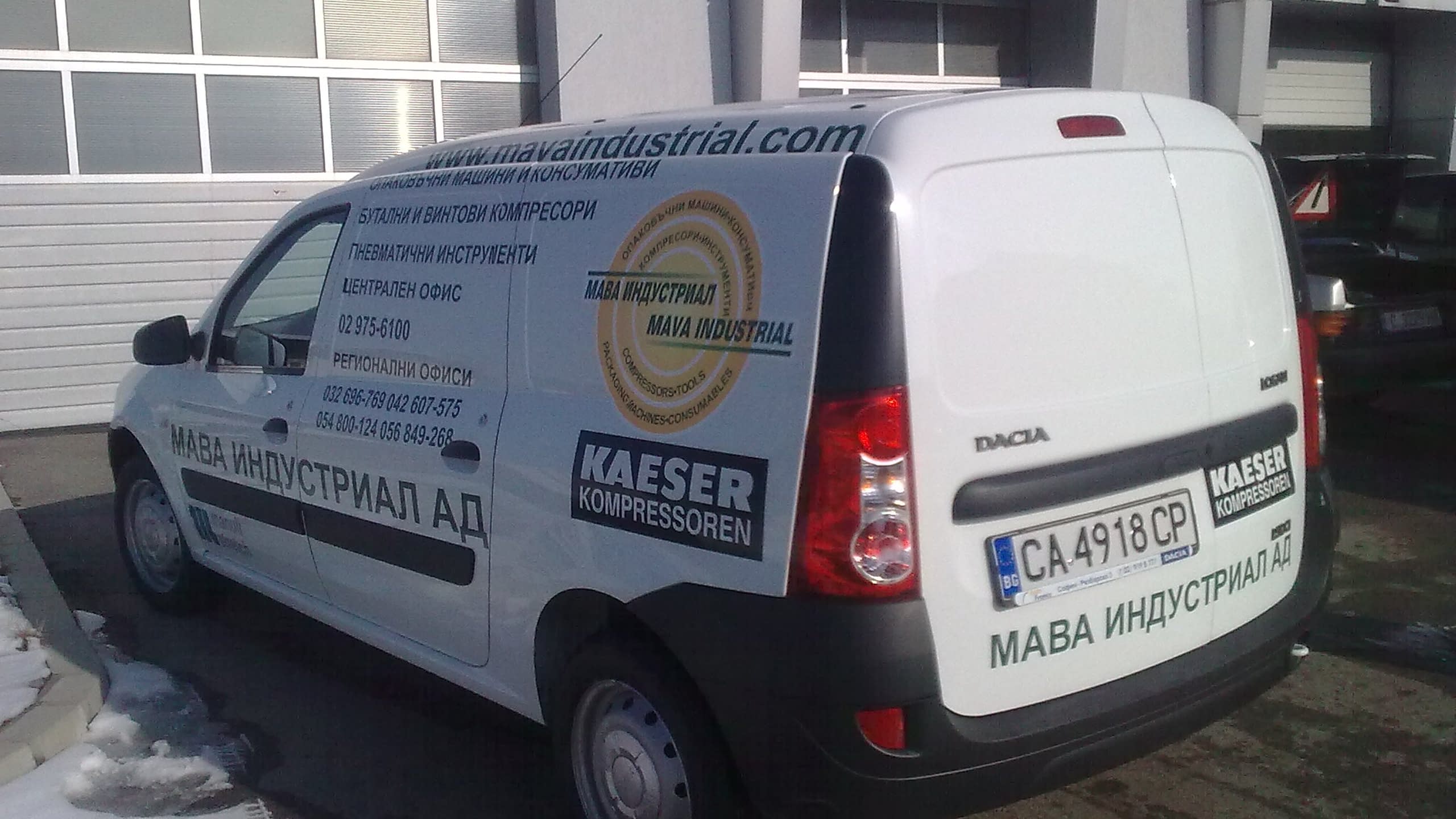 Бял служебен автомобил Дачия, заснет отстрани и отзад, облепен със сини и черни надписи с информация за фирма MAVA Industrial и лога на MAVA и KAESER.