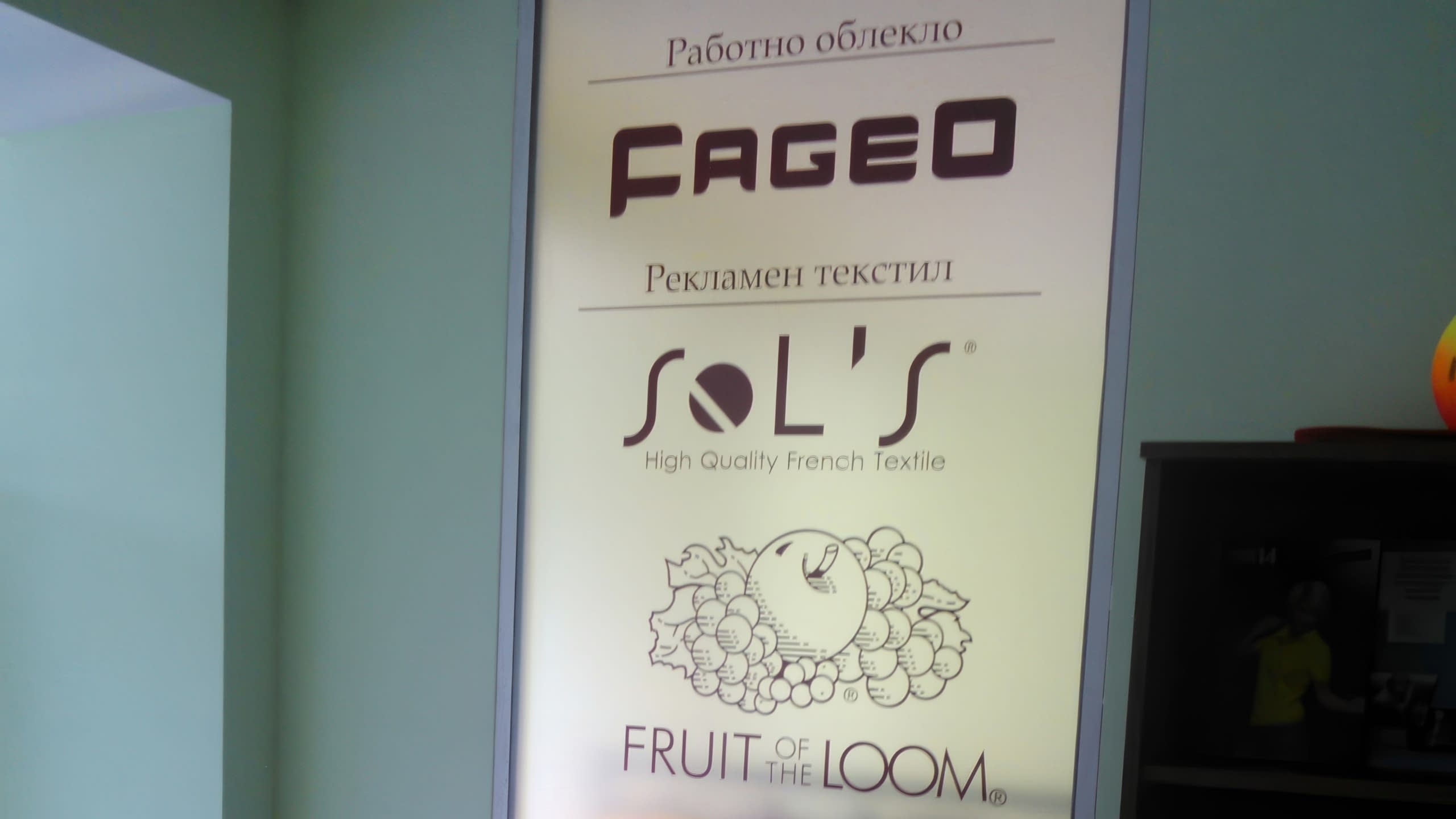 Близък план на светещ панел с лога на FAGEO, SOL'S и Fruit of the Loom.