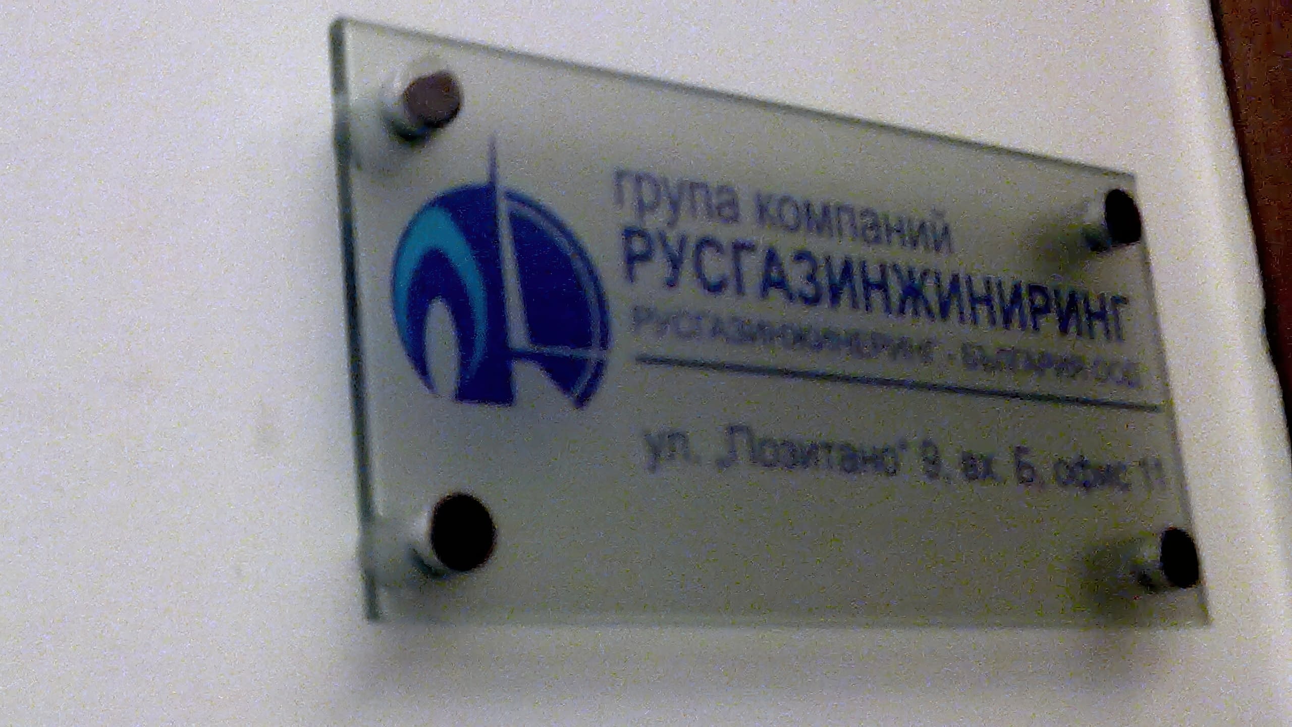 Фирмена табела на стена, заснета под ъгъл отдясно до тъмна врата.