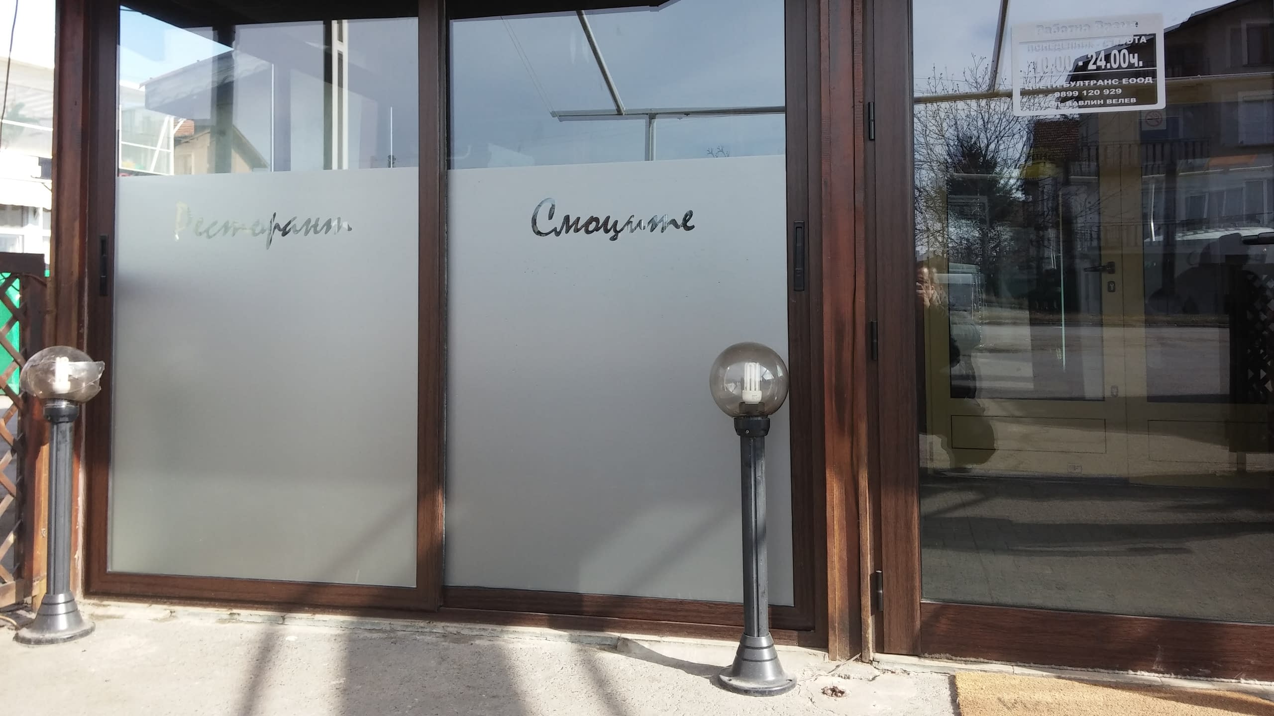 Входна врата на ресторант, декорирана с матирано фолио и изрязани надписи.