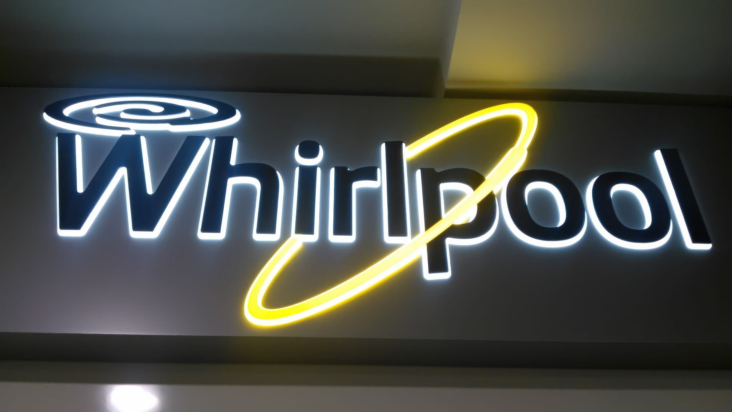 Лого на Whirlpool със светещи в бяло и жълто елементи на тъмен фон.