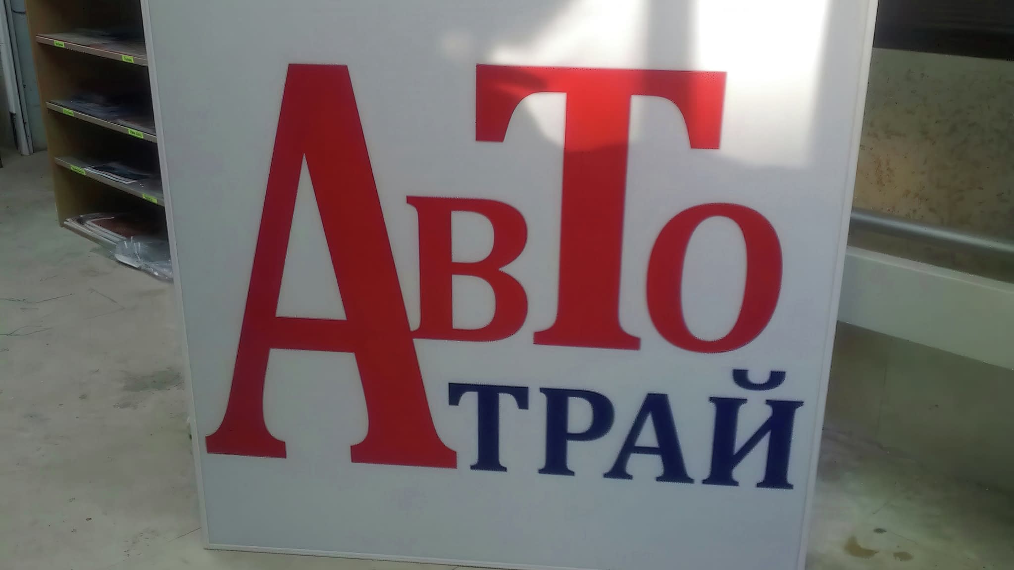 Светеща рекламна табела за бизнес 'Авто Трай' с големи червени и сини букви на бял фон – модерен пример за външна реклама с LED осветление.