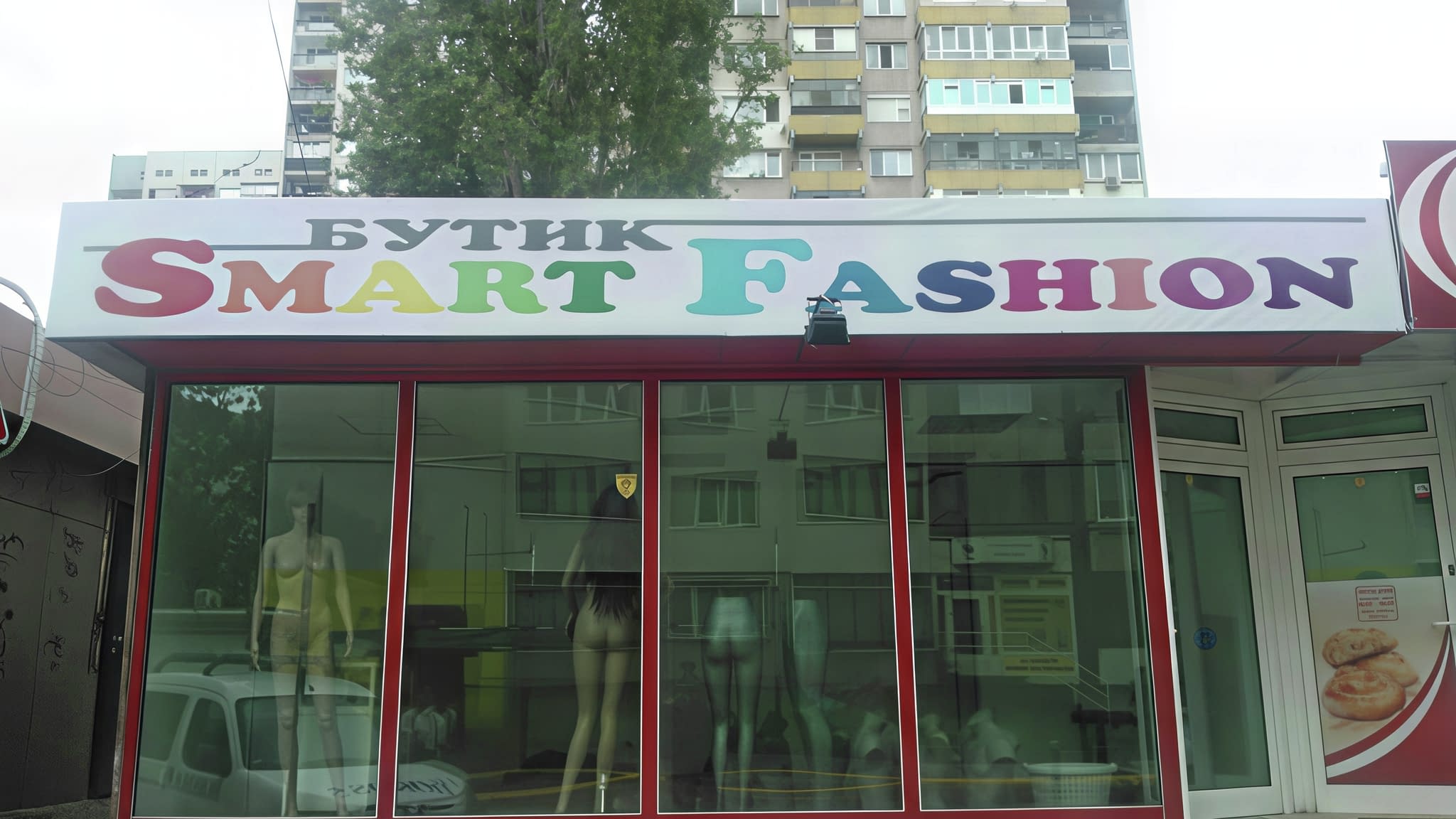 Рекламна табела за магазин – цветен надпис „Бутик Smart Fashion“ върху бяла фасада с големи стъклени витрини и изложени манекени.