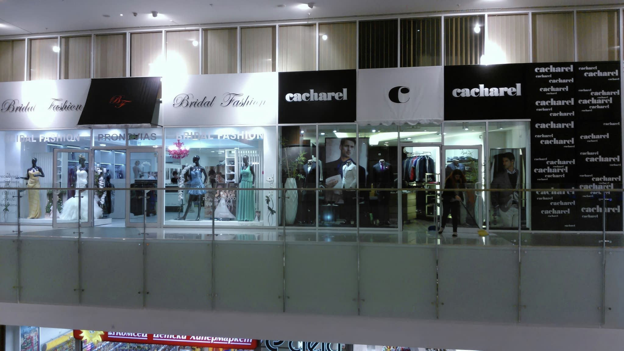 Изглед към фасадата на магазини „Bridal Fashion“ и „Cacharel“ с осветени витрини и LED светещи кутии в търговски център.