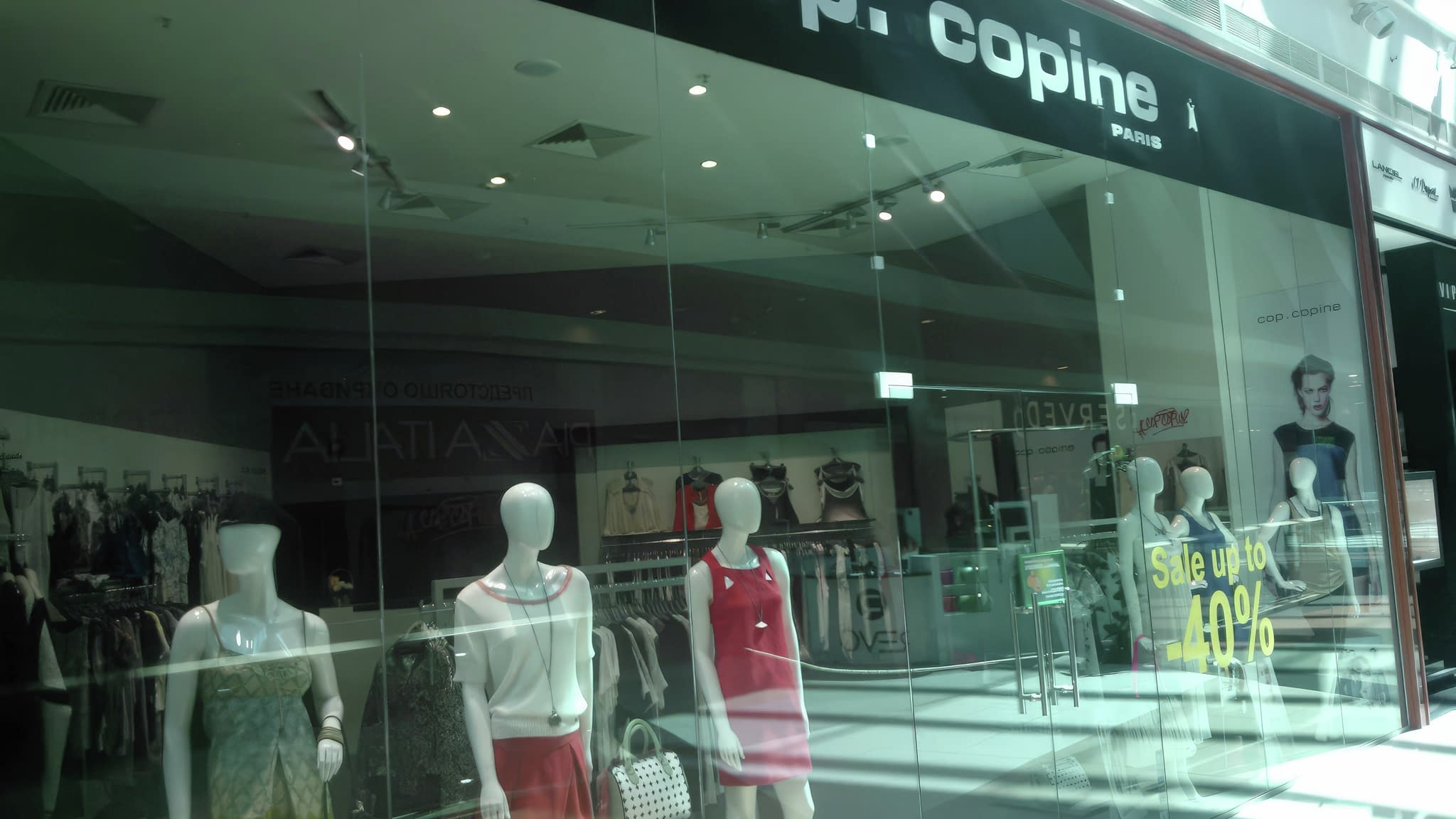 Витрина на магазин ‘cop. copine’ с манекени, облечени в модни тоалети, и рекламна табела за разпродажба с надпис ‘Sale up to 40%’.