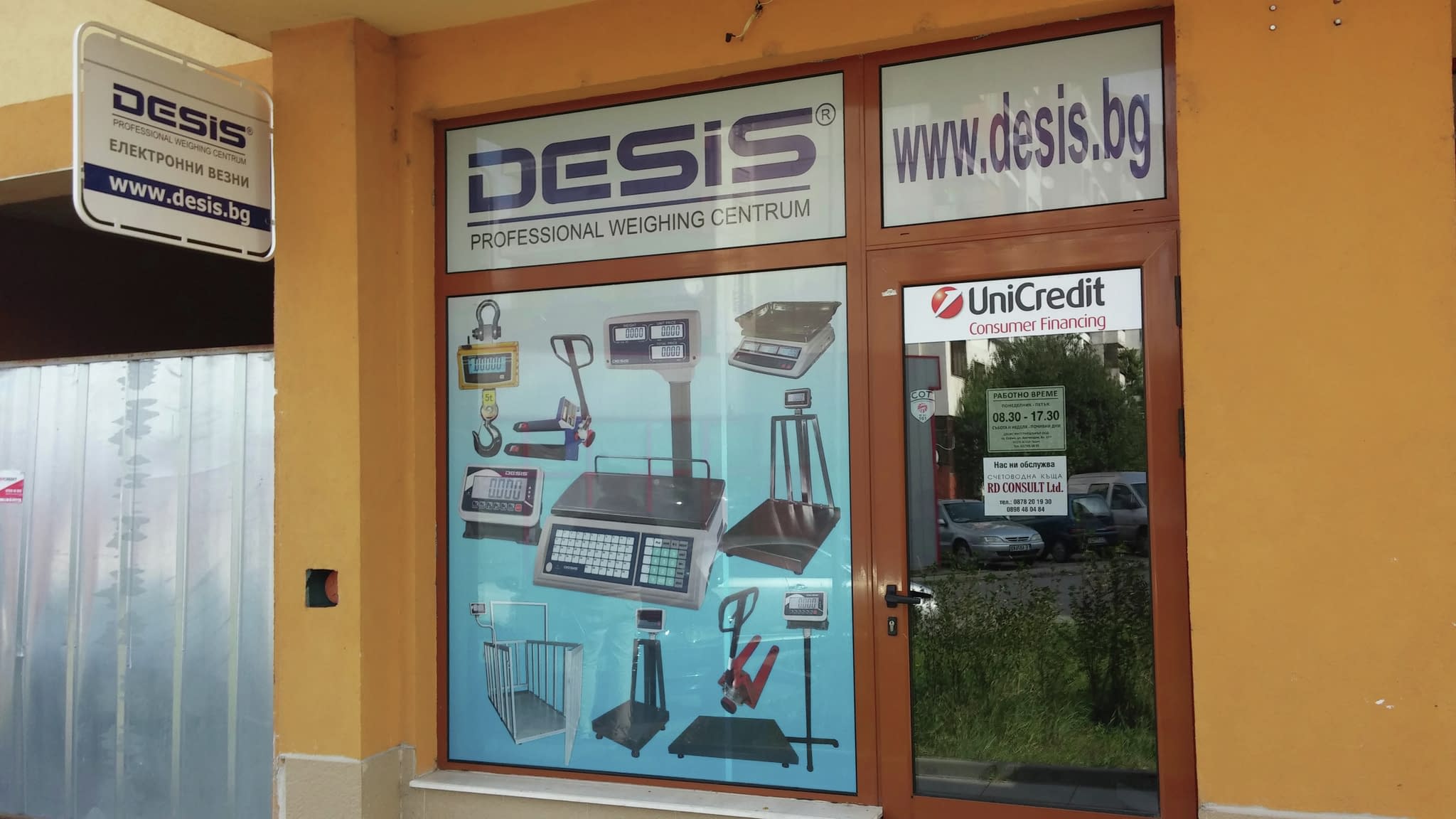 Брандирана витрина на магазин „Desis“ с перфо фолио, включваща рекламни изображения на електронни везни.