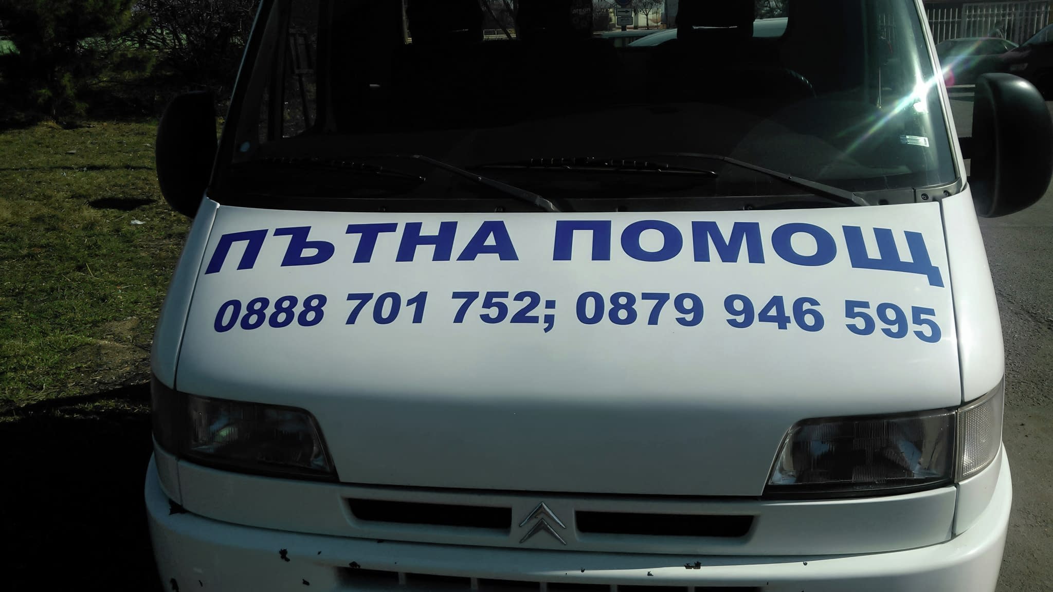 Брандиран бус на пътна помощ с телефонни номера за връзка.