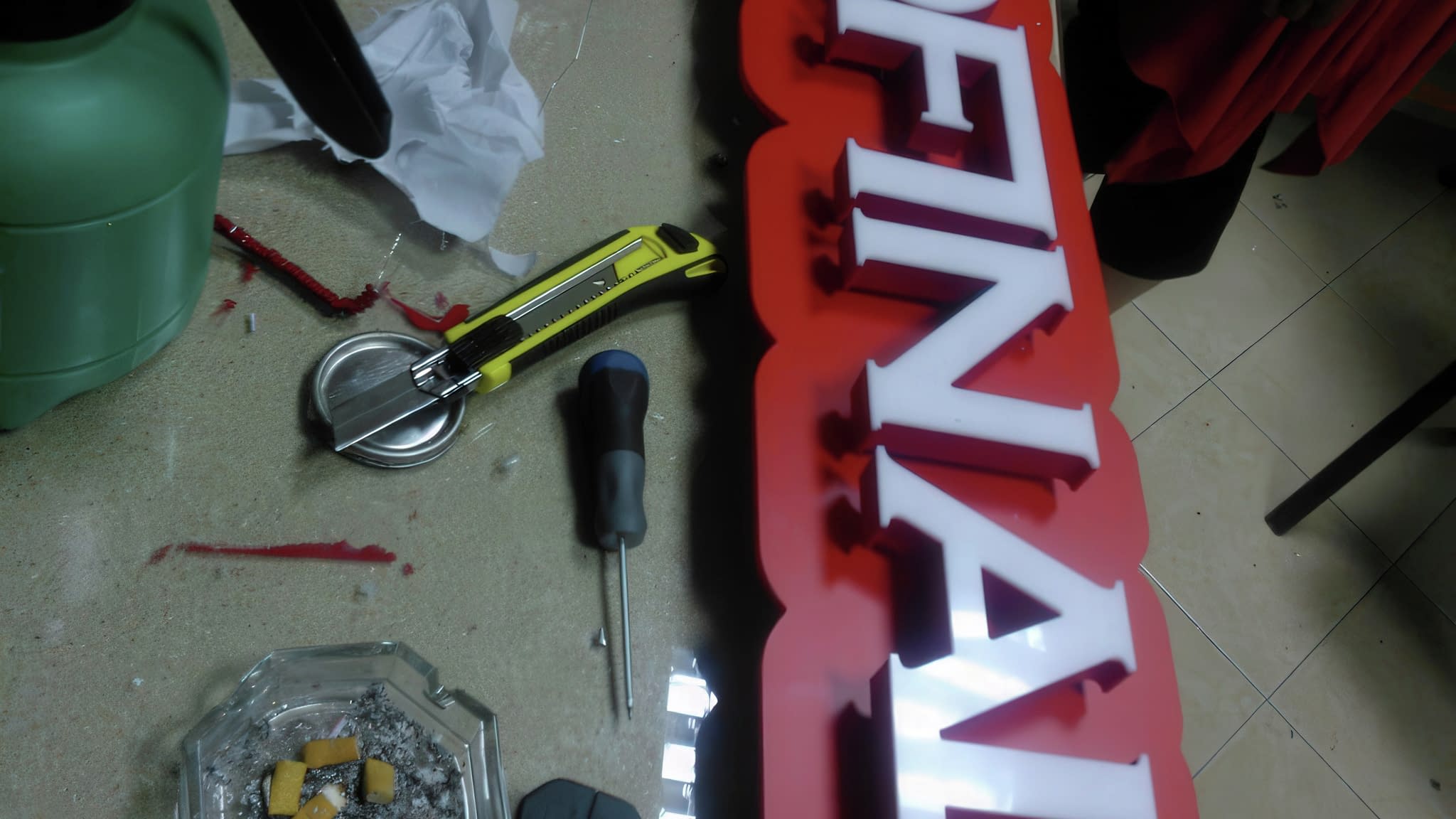 Табела 'EUROFINALE' с червен фон и бели букви, разположена върху маса за монтаж, заобиколена от инструменти и материали за сглобяване.