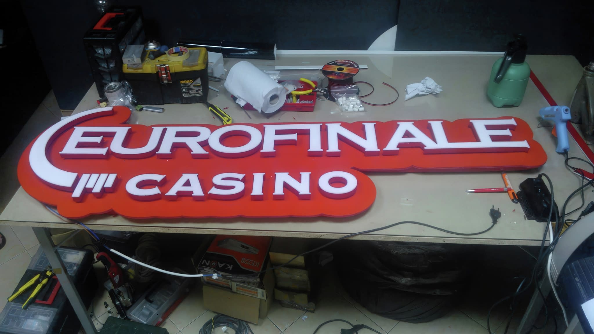 Червена LED табела 'EUROFINALE CASINO' с бели букви, позиционирана върху работна маса по време на изработка.