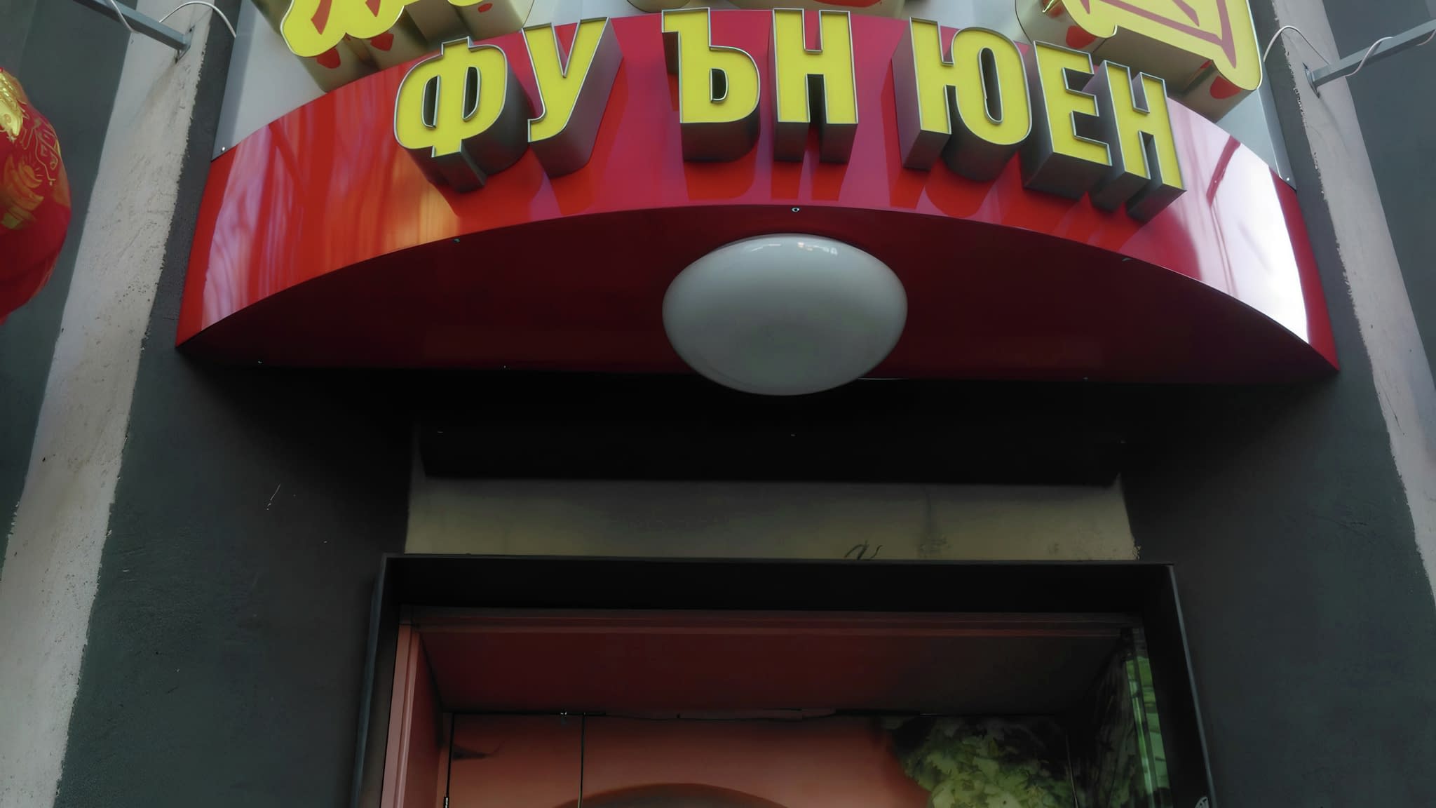 Светеща табела на ресторант „Фу Ън Юен“ с кирилски надпис и китайски йероглифи върху червен фон, акцентирана с декоративни детайли.