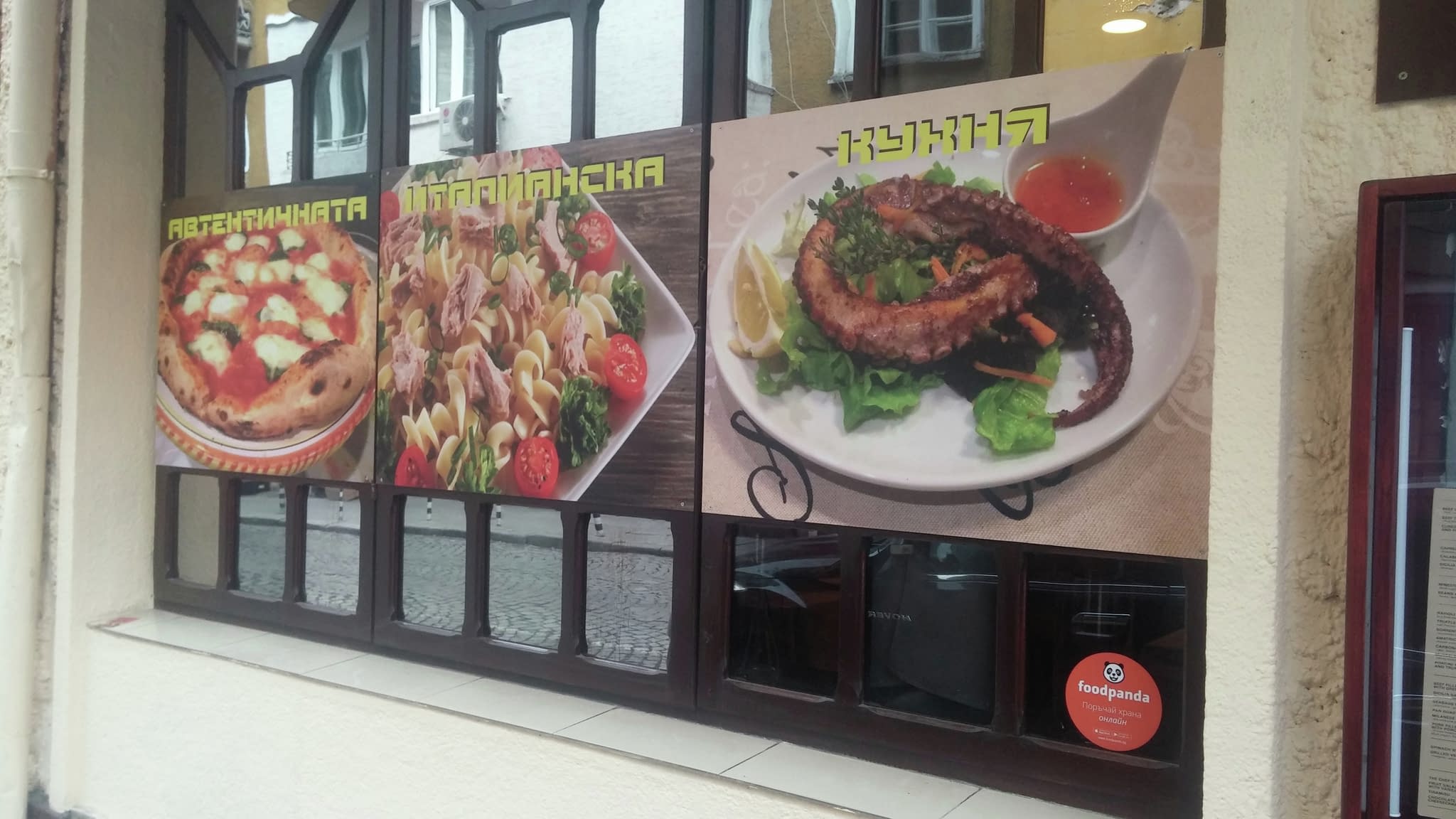 Витрина на ресторант с изображения на автентична италианска пица, паста със зеленчуци и октопод на скара с лимон – привлекателна външна реклама.