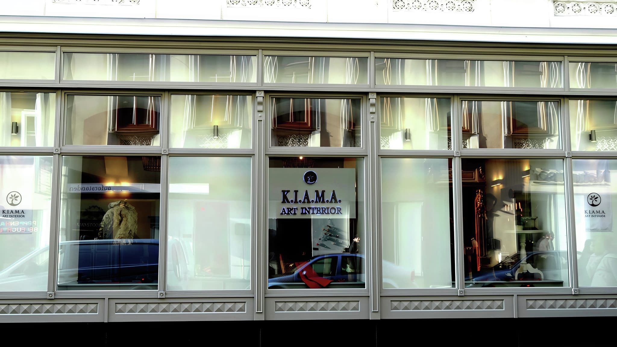 Рекламна табела на витрина – стилен фирмен надпис 'K.I.A.M.A. Art Interior' на магазин за интериорен дизайн.