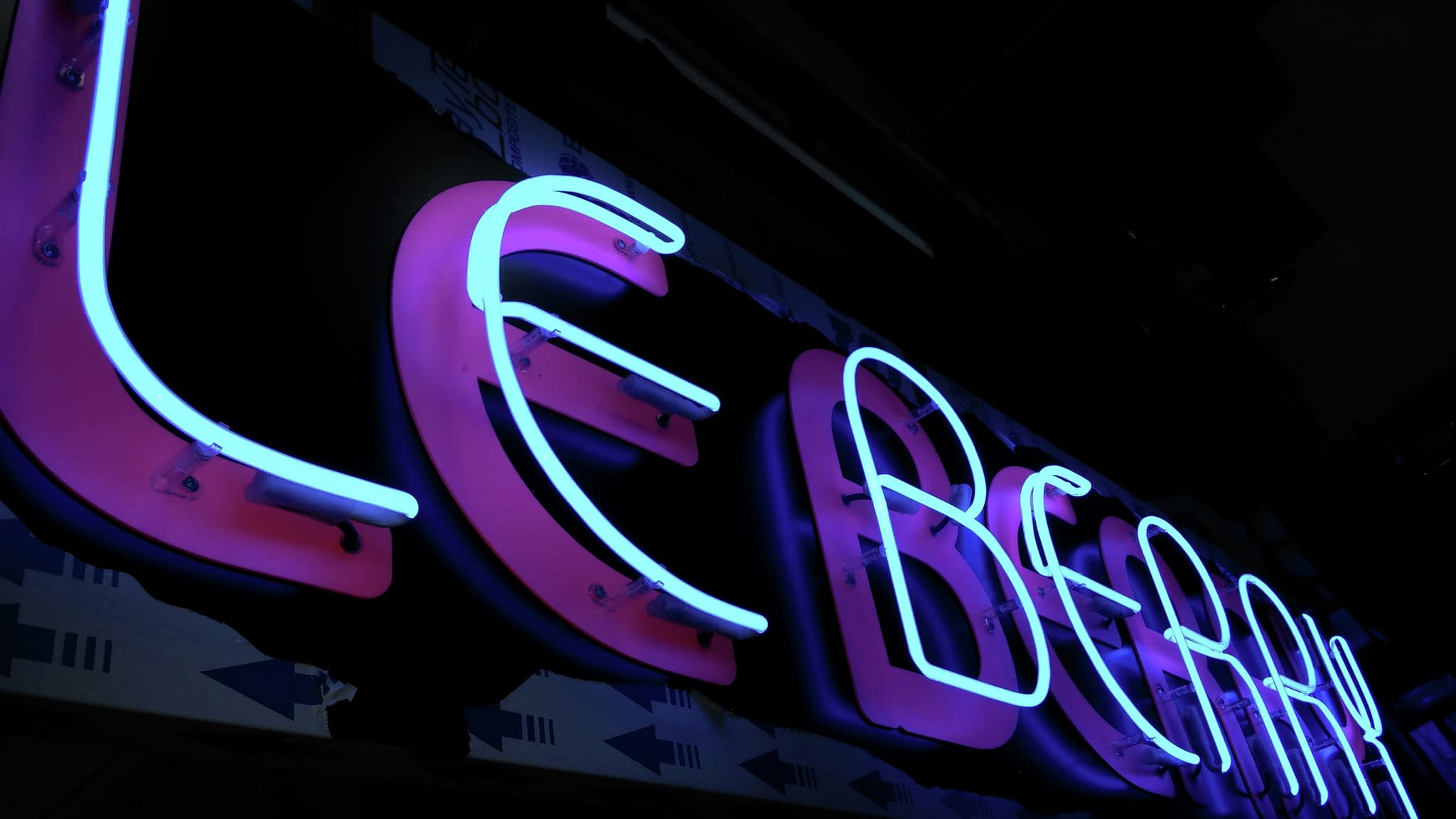 Неонов знак „Le Berry“ със синьо-розово сияние – привличаща погледа модерна реклама за нощни заведения.