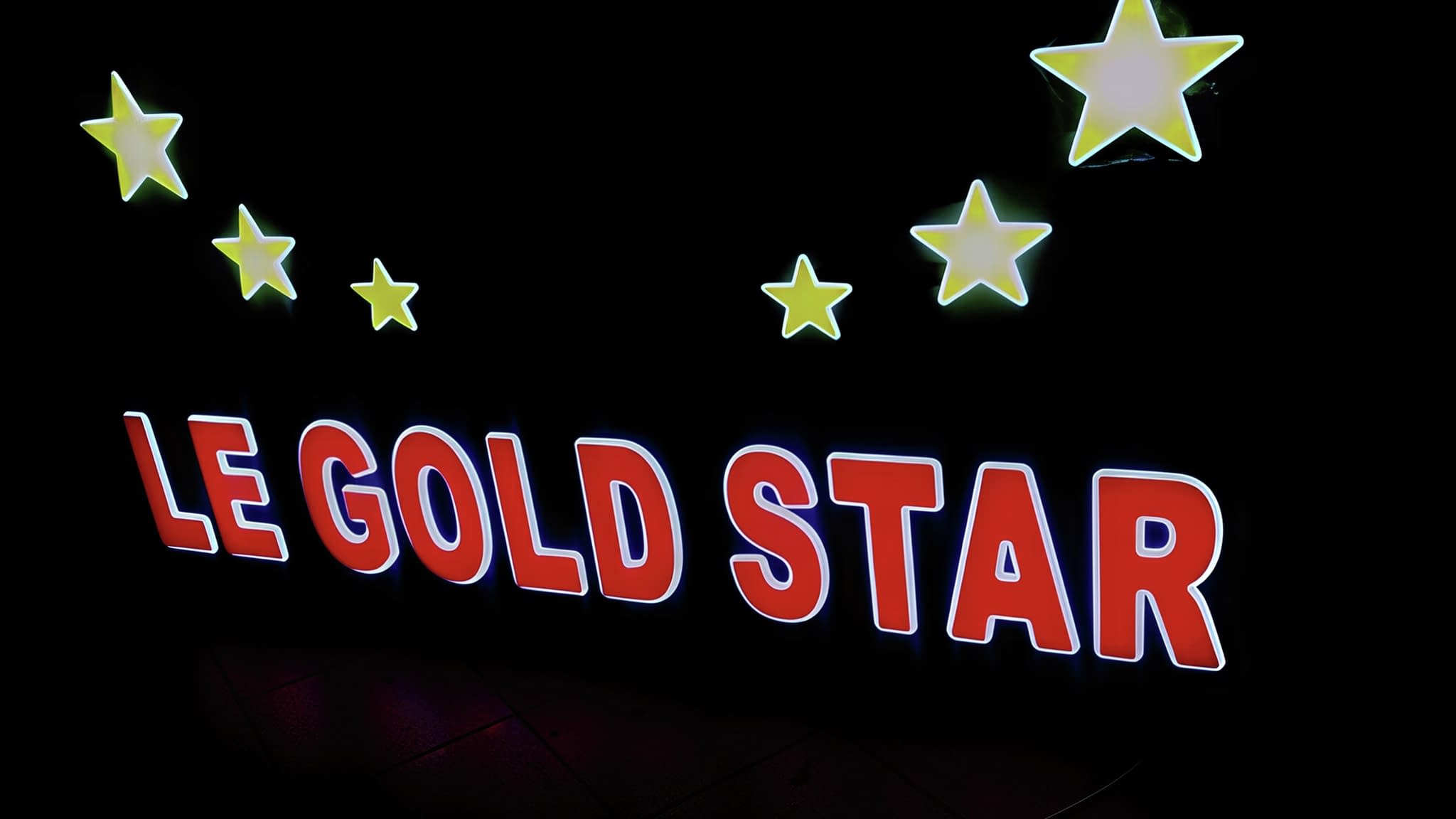 Светеща табела "Le Gold Star" с LED осветление и ярки жълти звезди на черен фон – стилно решение за нощна реклама на магазини и бизнеси.