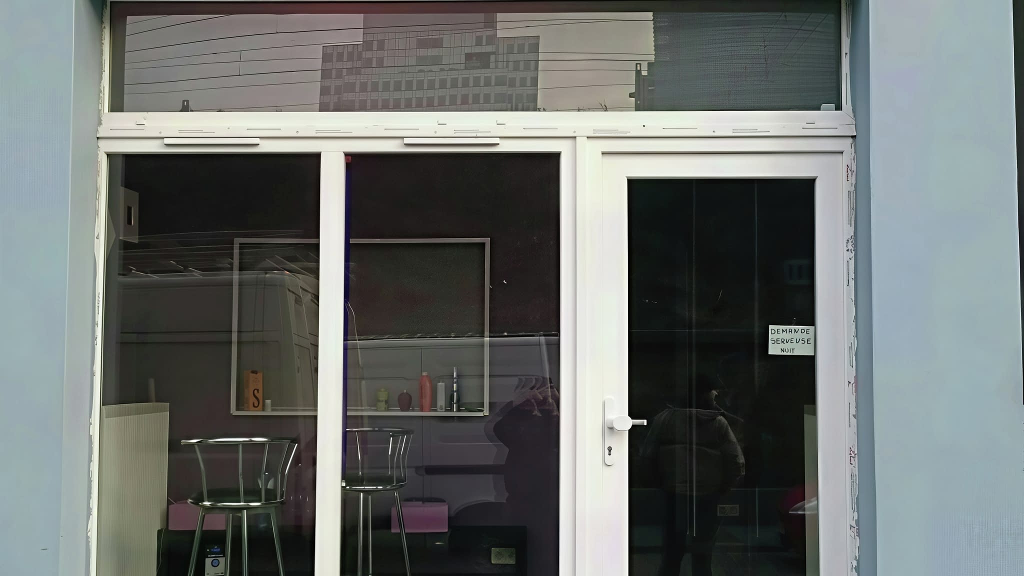 Неонова реклама „LE MIAMI” със синя светлина върху фасада на заведение.