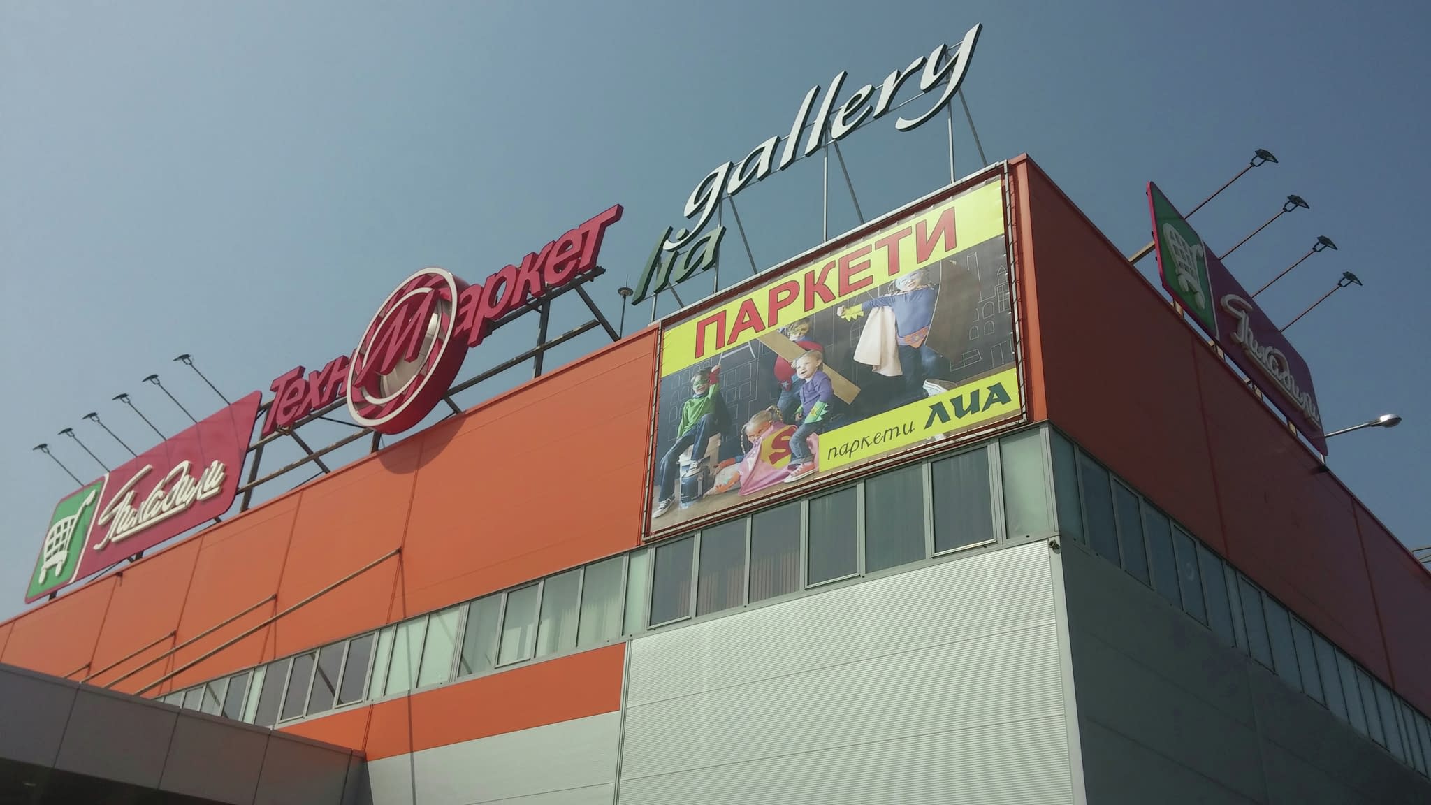 Голямо винилово рекламно пано върху търговски център – ефективна външна реклама с висока видимост.