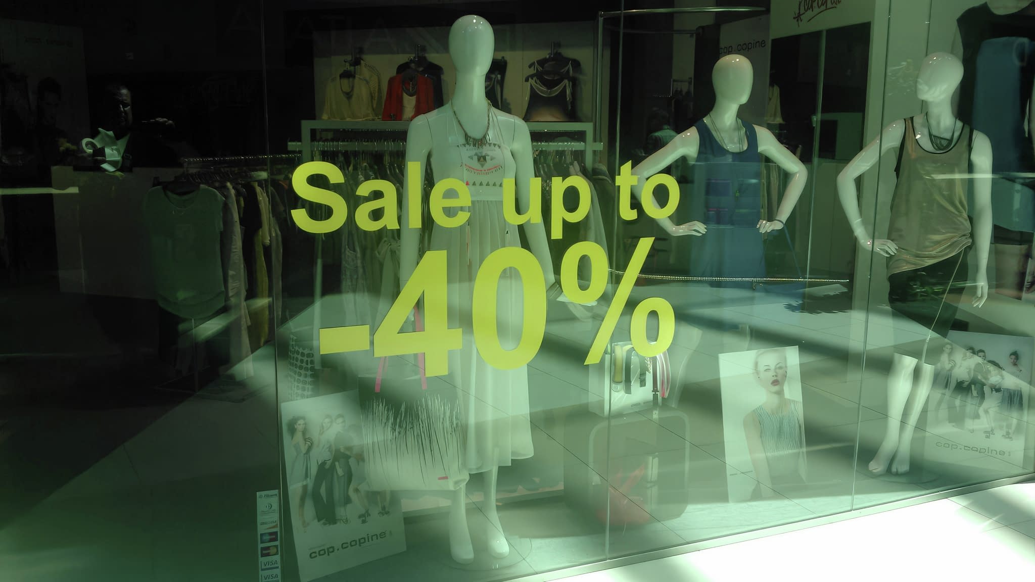 Прозорец на моден магазин с промоционален надпис „Разпродажба до -40%“ и манекени, облечени в елегантни тоалети.