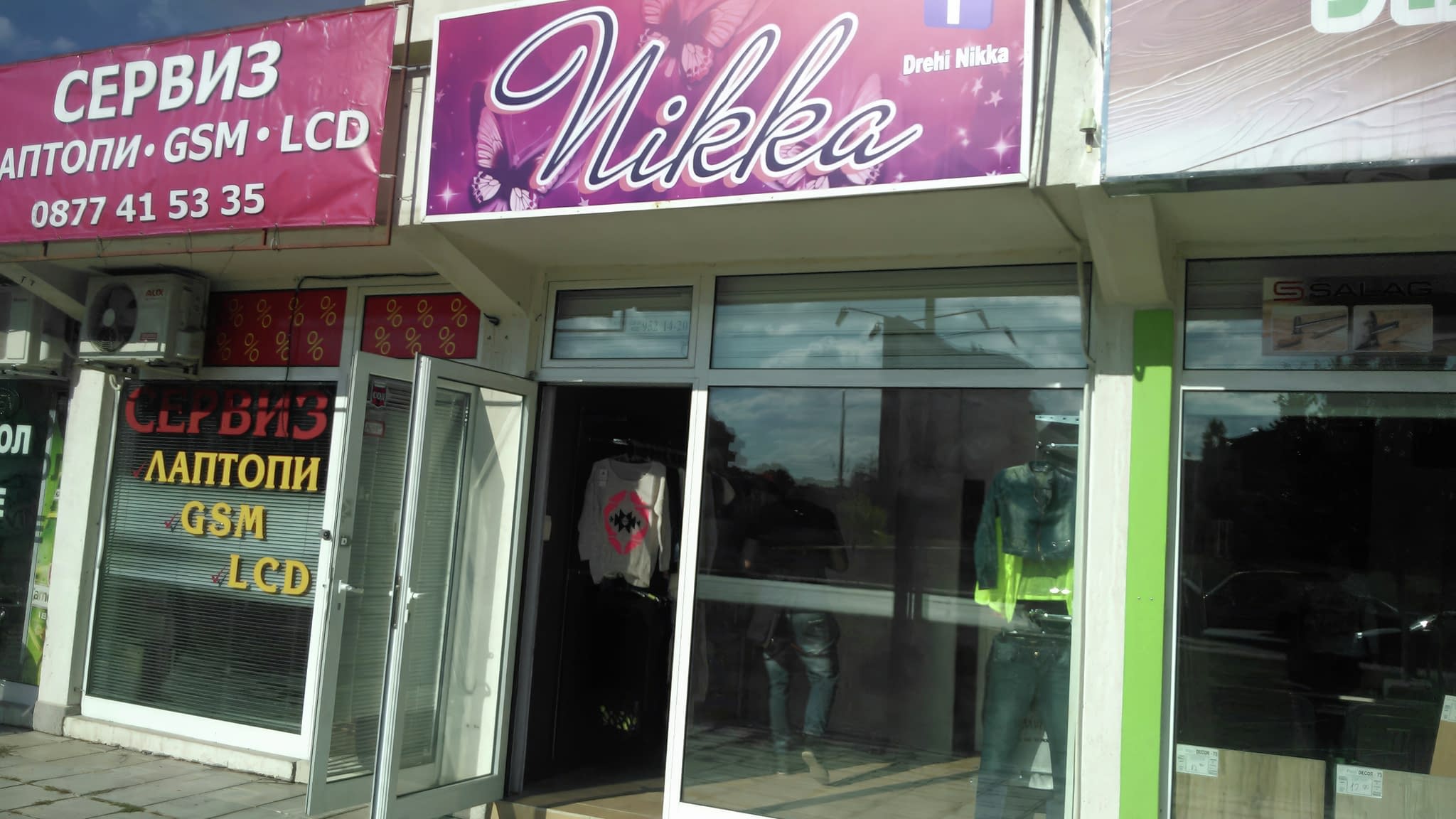 Винилов банер с ярък дизайн пред магазин за дрехи.