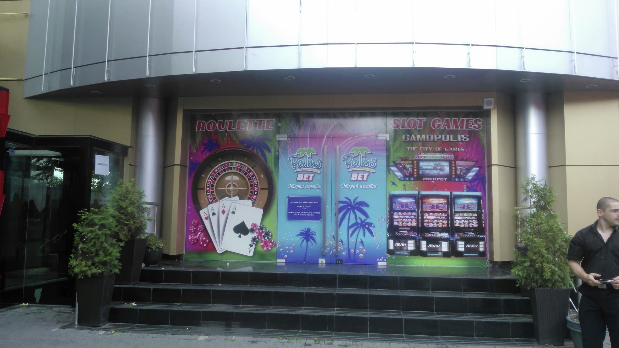 Рекламно фолио за витрини на казино „Palms Bet“ с ярки графики на рулетка, покер карти и слот машини.