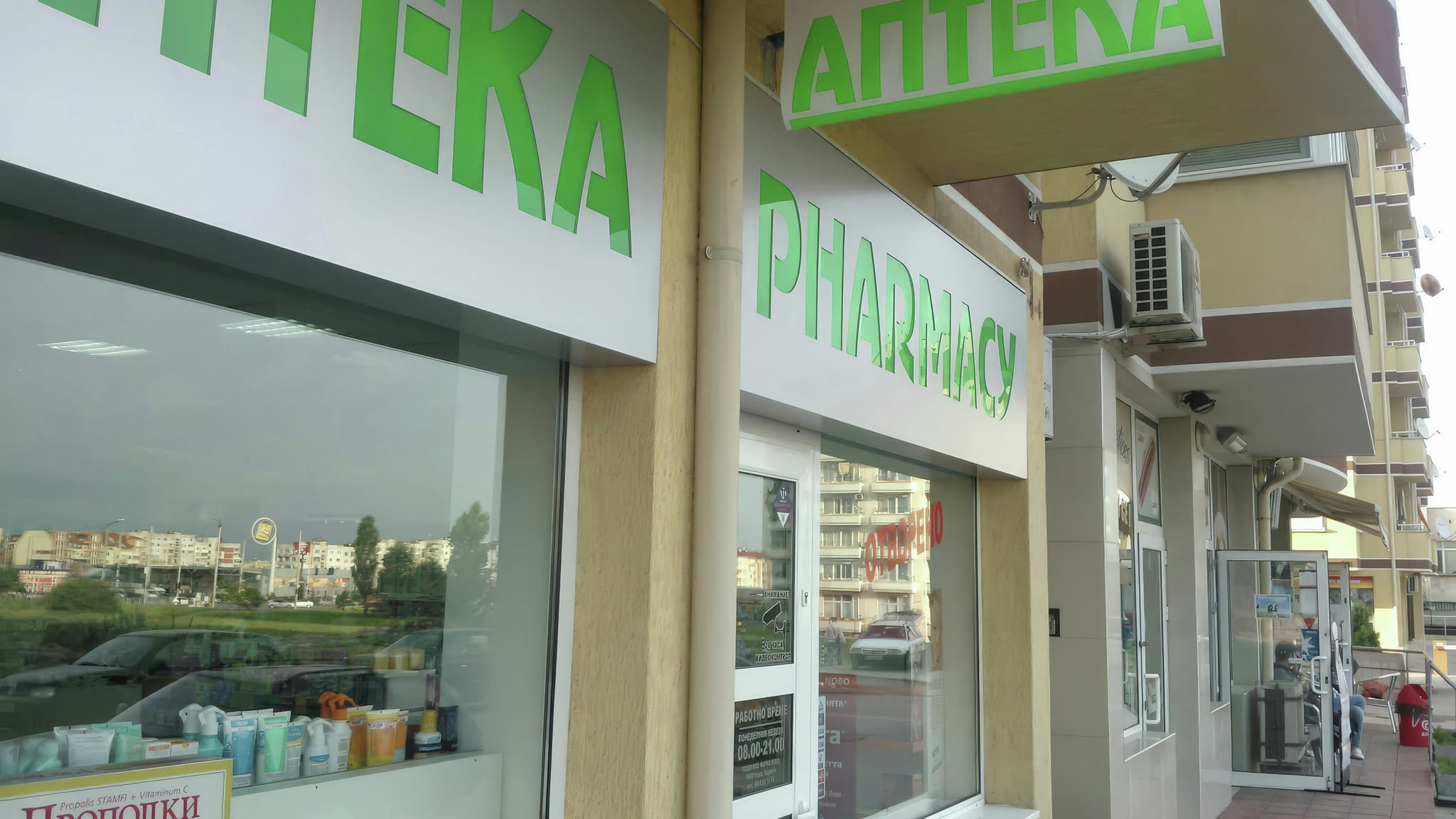 Транспарант с надпис „Аптека“ и „Pharmacy“ – двуезичен рекламен винилов банер за аптека, разположен над входа.