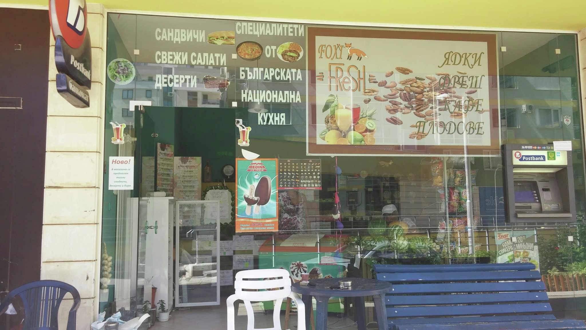 Витрина на кафене с рекламни стикери, изобразяващи меню с българска национална кухня, салати и десерти, както и банкомат отстрани.
