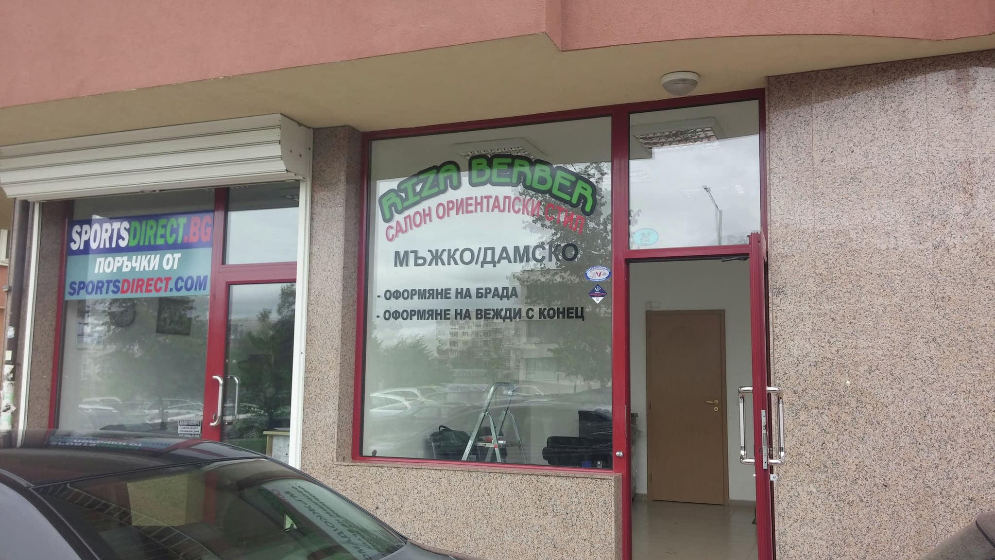 Витрина на бръснарски салон с рекламни стикери, изобразяващи информация за мъжки и дамски услуги, включително оформяне на брада и вежди.