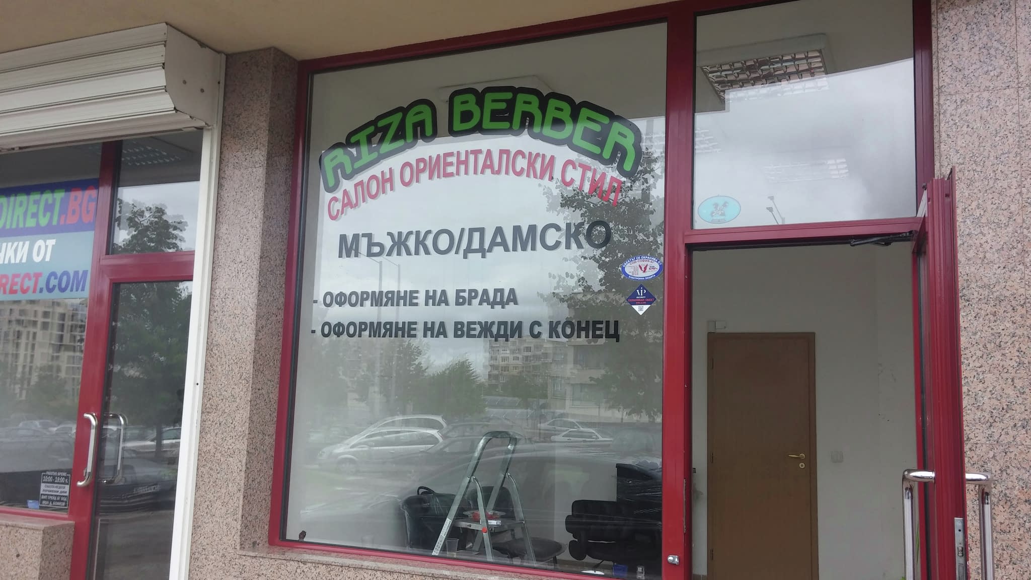 Витрина на бръснарски салон ‘Pizza Berber’ с рекламни стикери, включващи надписи за мъжки и дамски услуги, оформяне на брада и вежди.