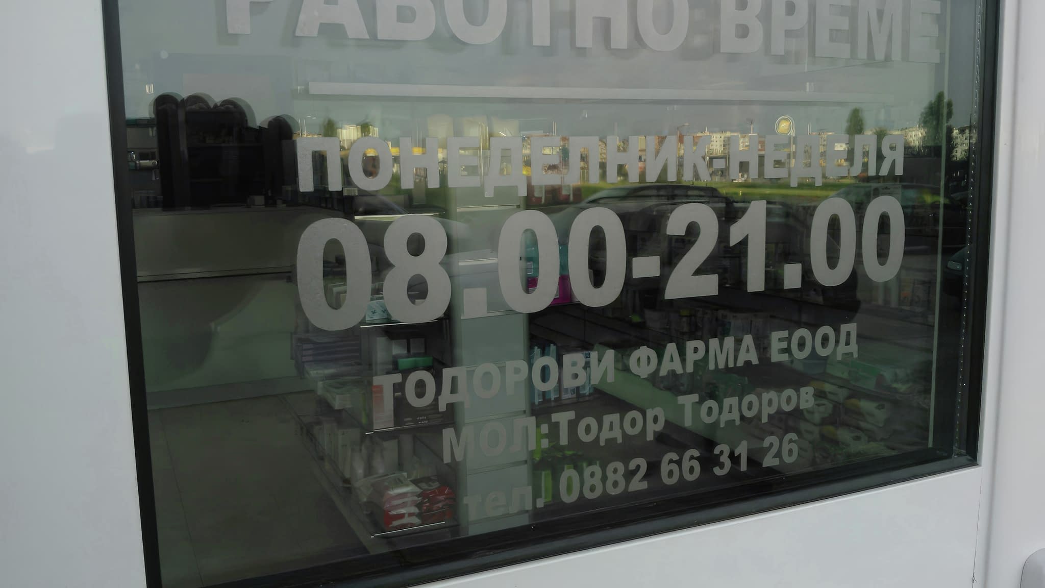 Самозалепващ стикер за работно време, залепен на стъклена витрина с прозрачно фолио и надпис в бяло.