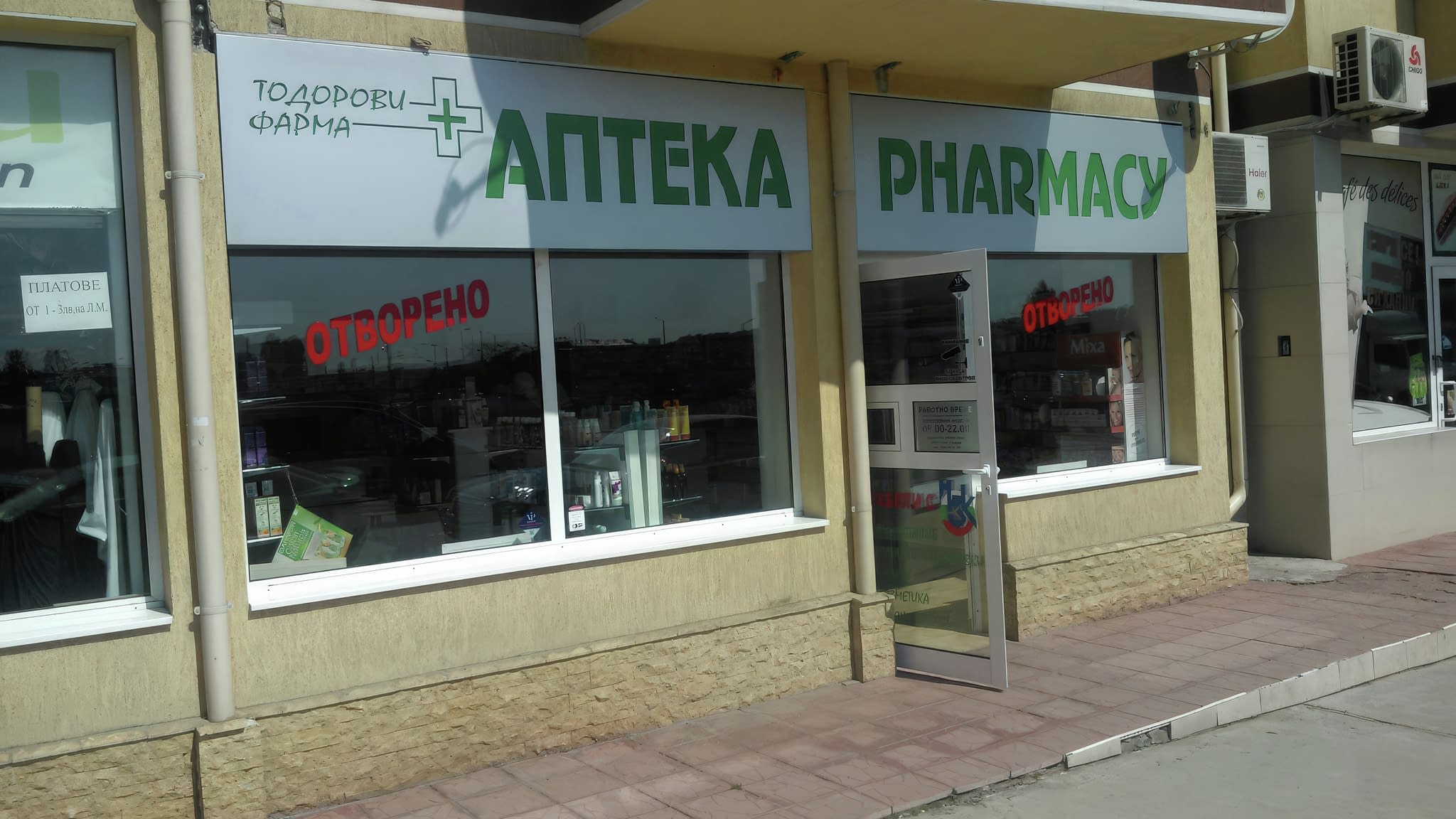 Витрина на аптека с големи надписи 'АПТЕКА' и 'PHARMACY', допълнена с червен LED знак 'ОТВОРЕНО' – привлекателна външна реклама за клиенти.