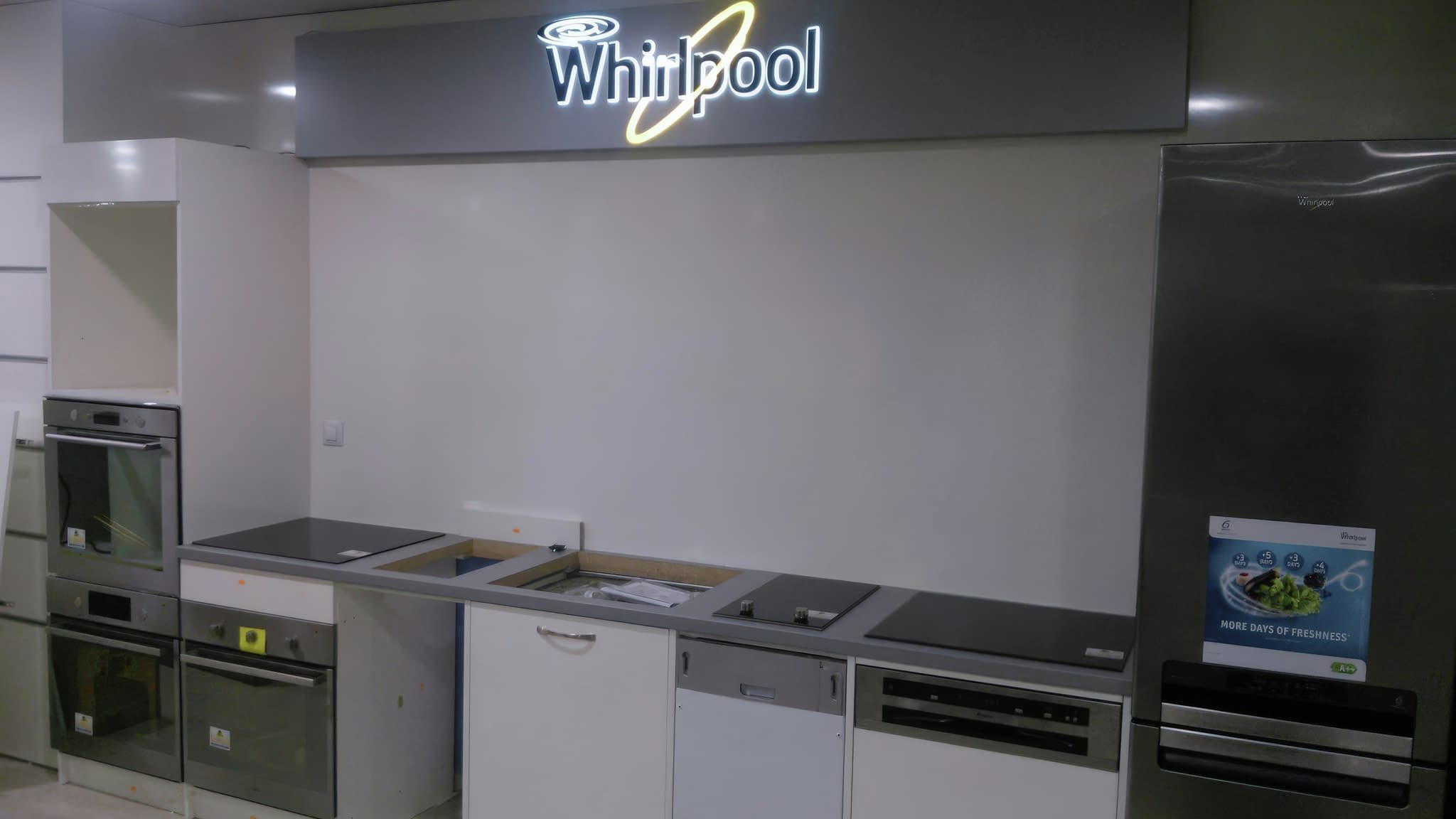 Модерен кухненски дисплей с вградени уреди Whirlpool и светещо лого.