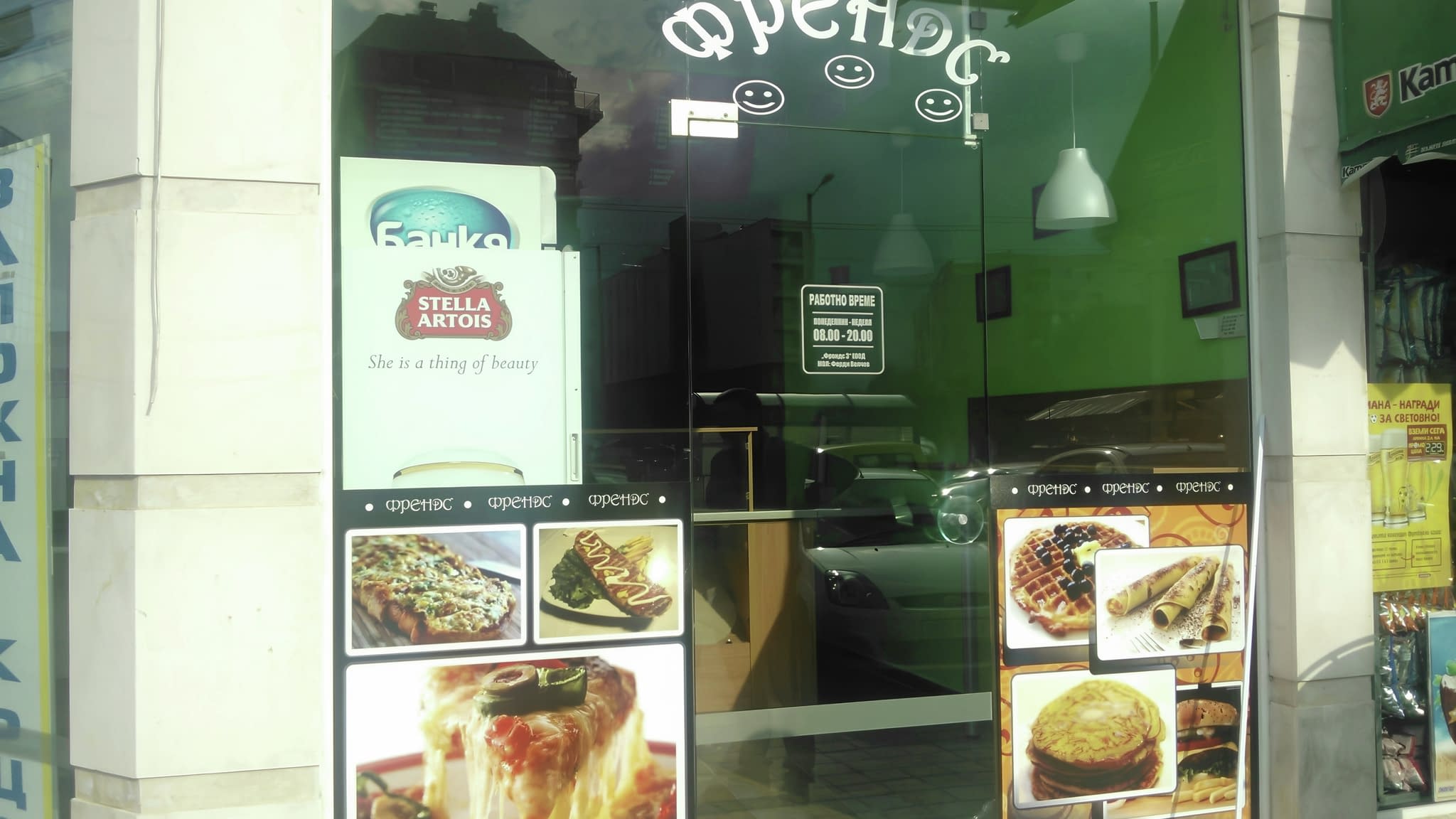 Рекламно фолио за пицария – витрина с изрязани бели букви „Пица на парче – Френдс“ и апетитни изображения на пица, гофрети и палачинки, оформено с фолио за заведения.