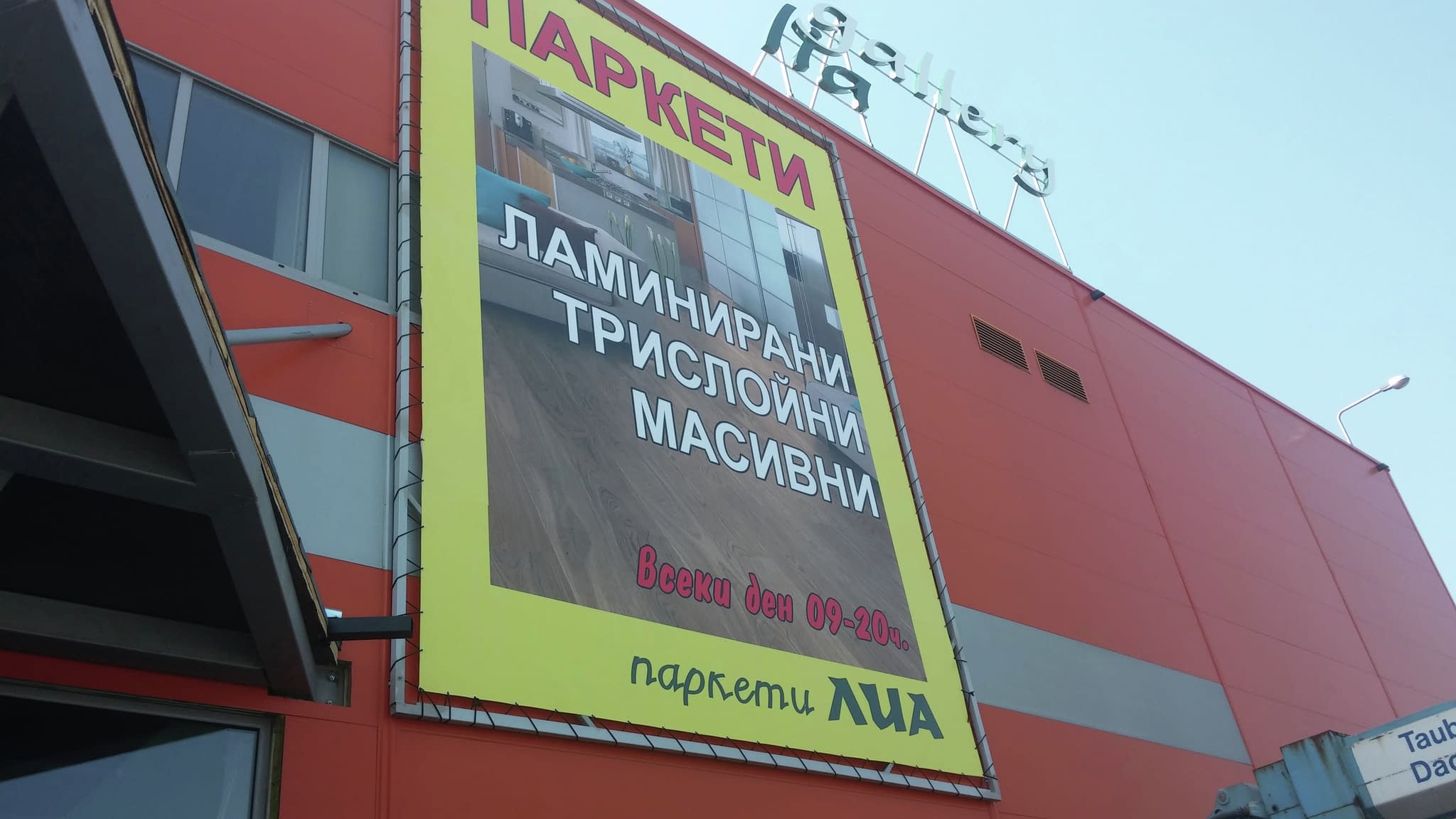 Голям винилов банер за паркети с жълта рамка, рекламиращ ламинирани и масивни подови настилки.