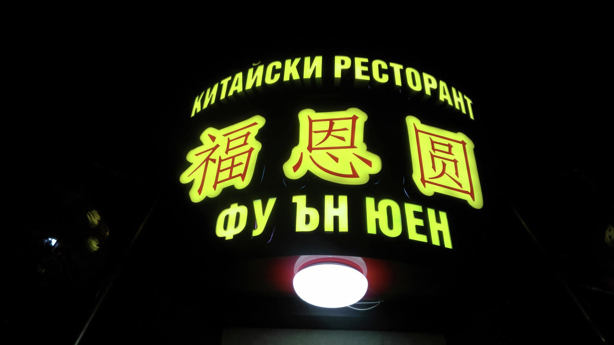 Светеща табела за китайски ресторант 'Фуън Юен' с жълти китайски символи на черен фон.