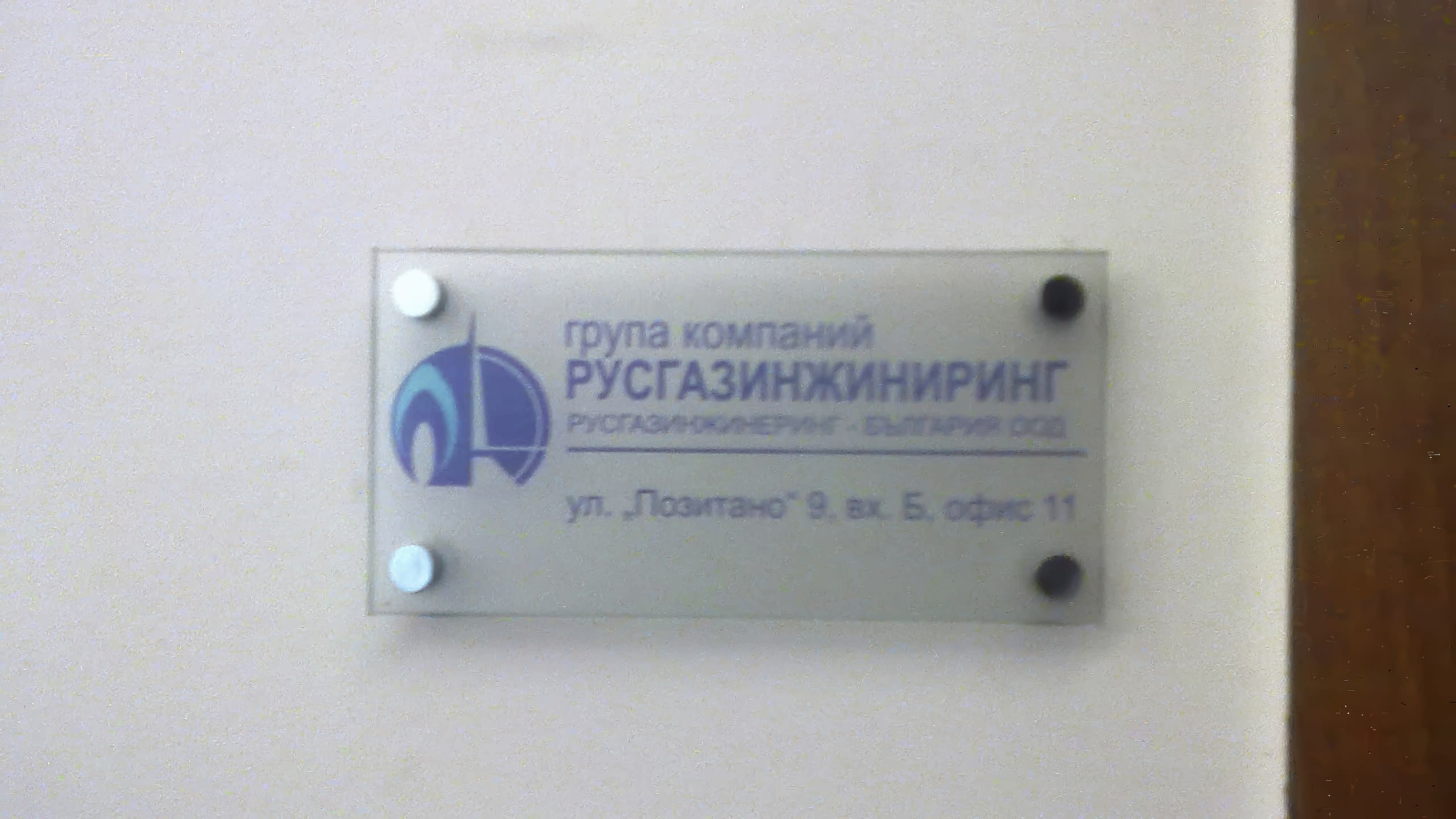 Фирмена табела за офис от матиран плексиглас с лого и адрес на "РУСГАЗИНЖИНИРИНГ", монтирана с метални дистанционери.