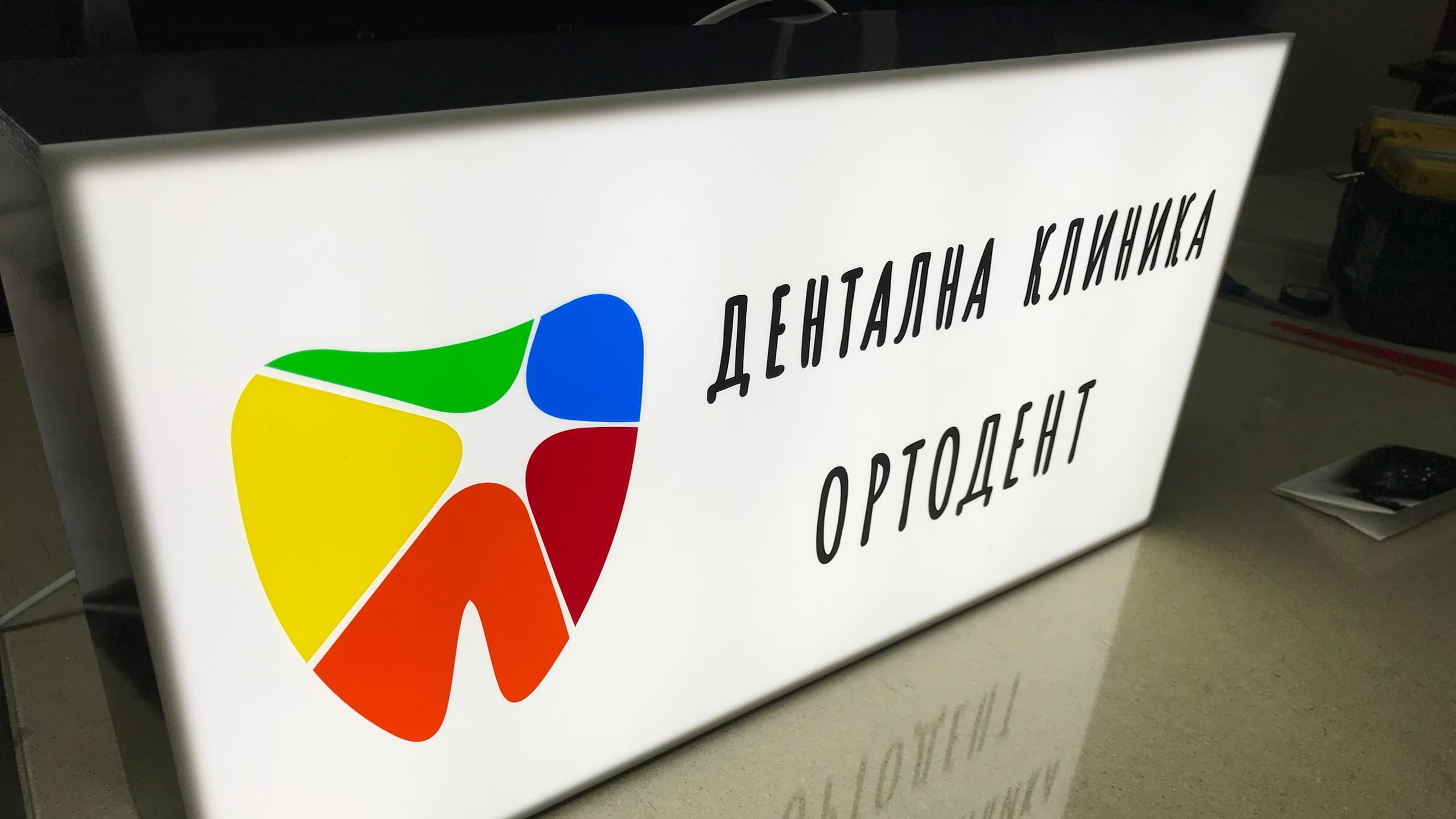 Светеща рекламна табела тип лайтбокс за офис на "Дентална клиника ОРТОДЕНТ" с цветно лого.